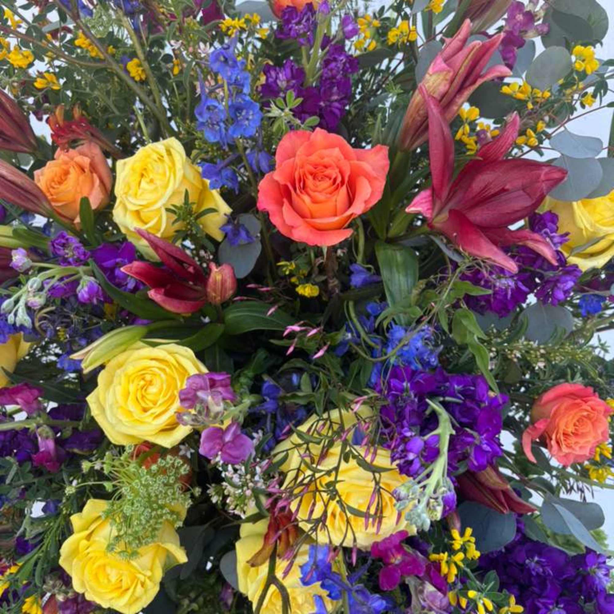 Colorful bouquet with roses, lilies, and purple-blue filler flowers