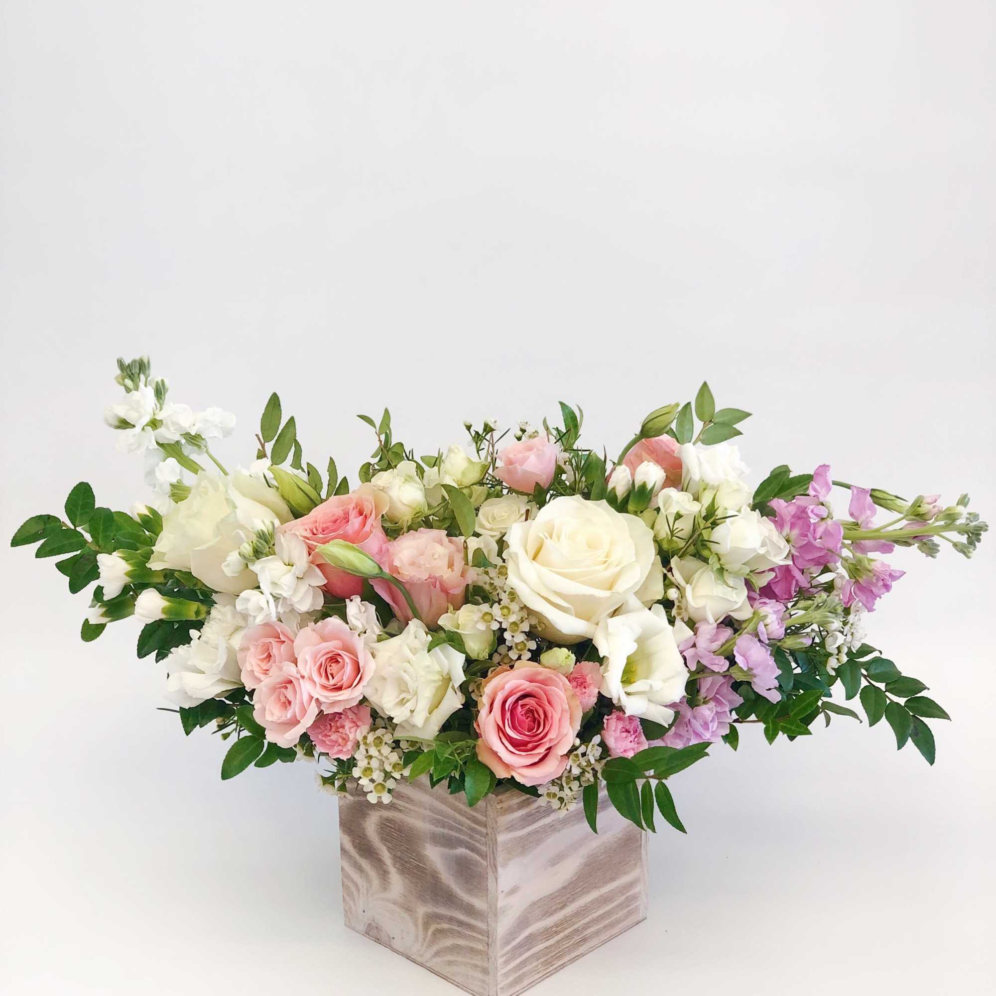 Mixed pink, white, and lavender flowers in a square vase