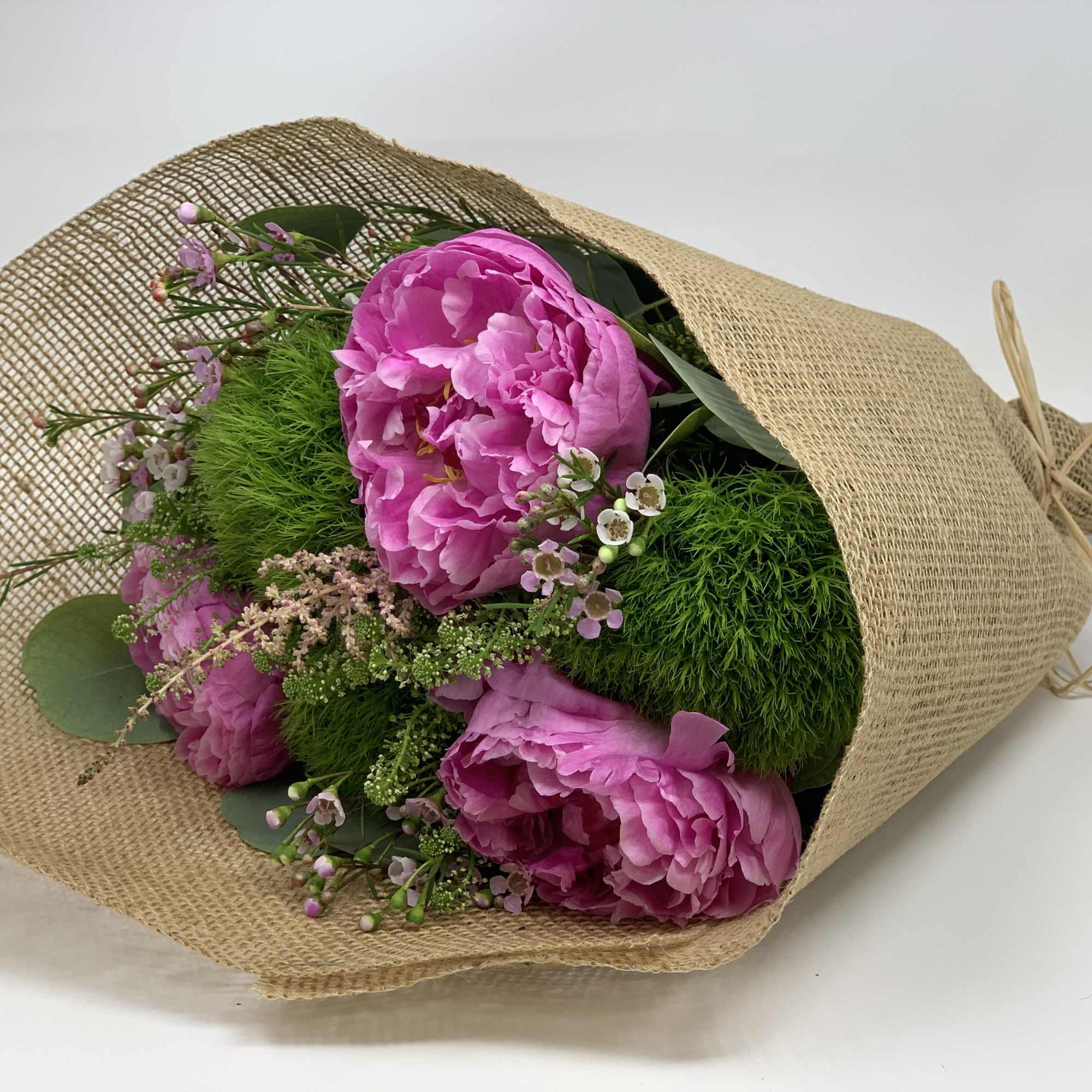 Pink peonies wrapped in burlap with small filler flowers