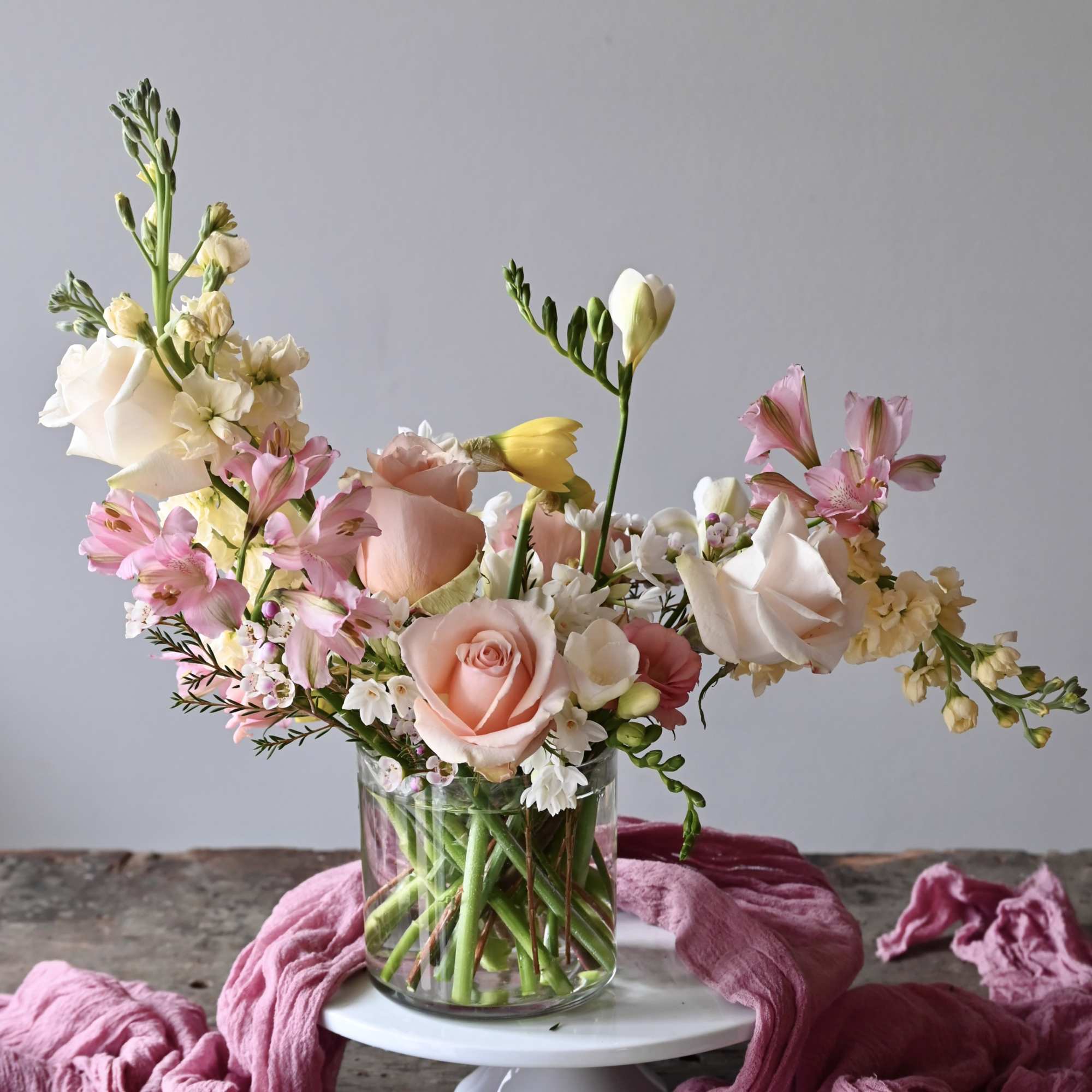Mixed pastel flowers arranged in a clear glass vase