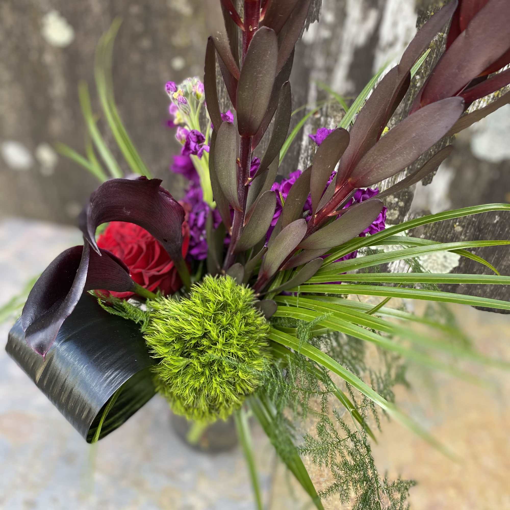 Bouquet with a red rose, purple flowers, and dark foliage