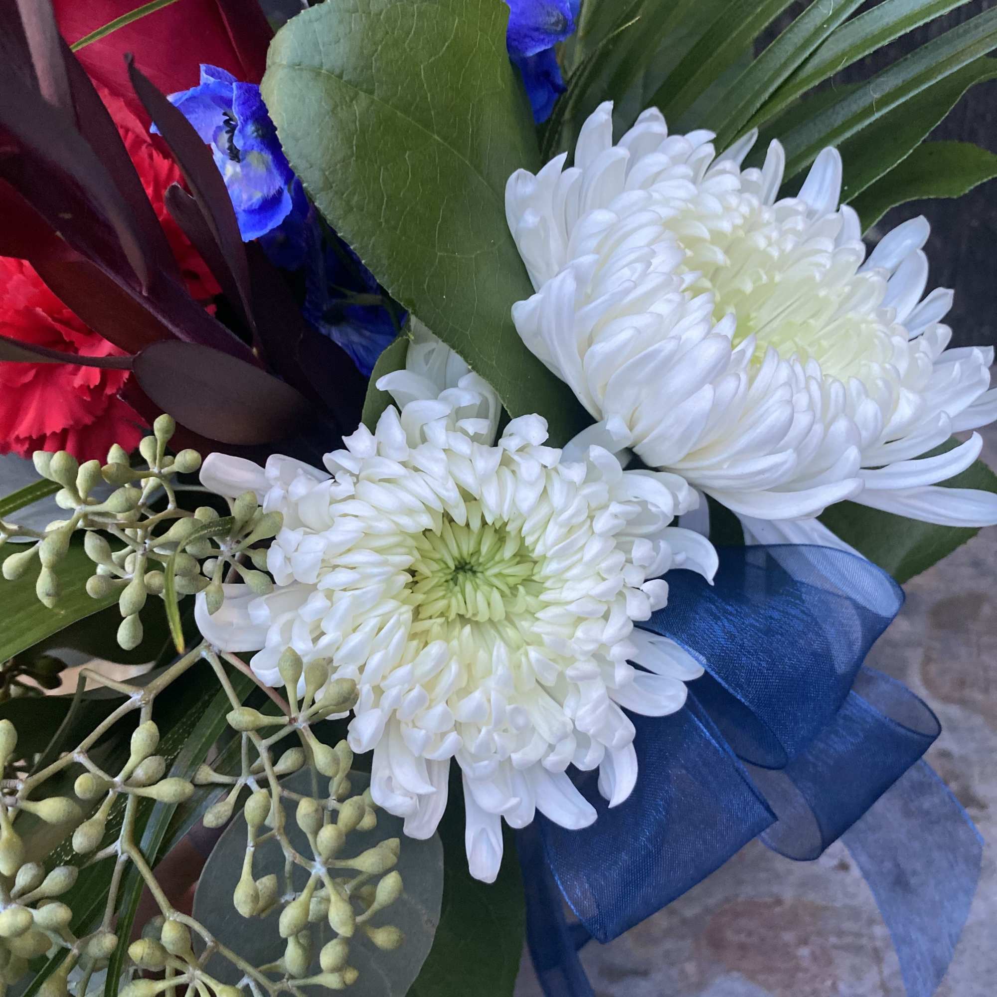 Bouquet with white chrysanthemums, red roses, and blue ribbon