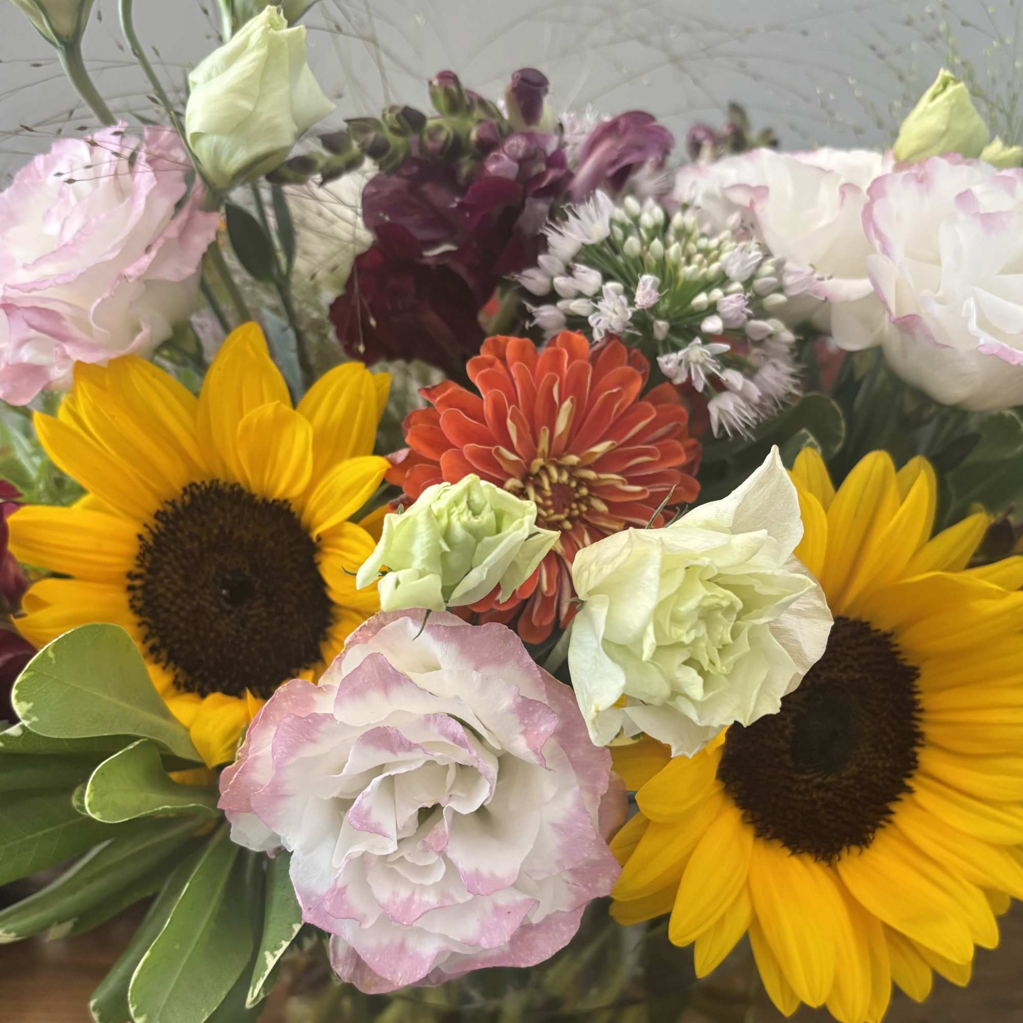 Mixed bouquet with sunflowers, pink and white blooms, and burgundy flowers