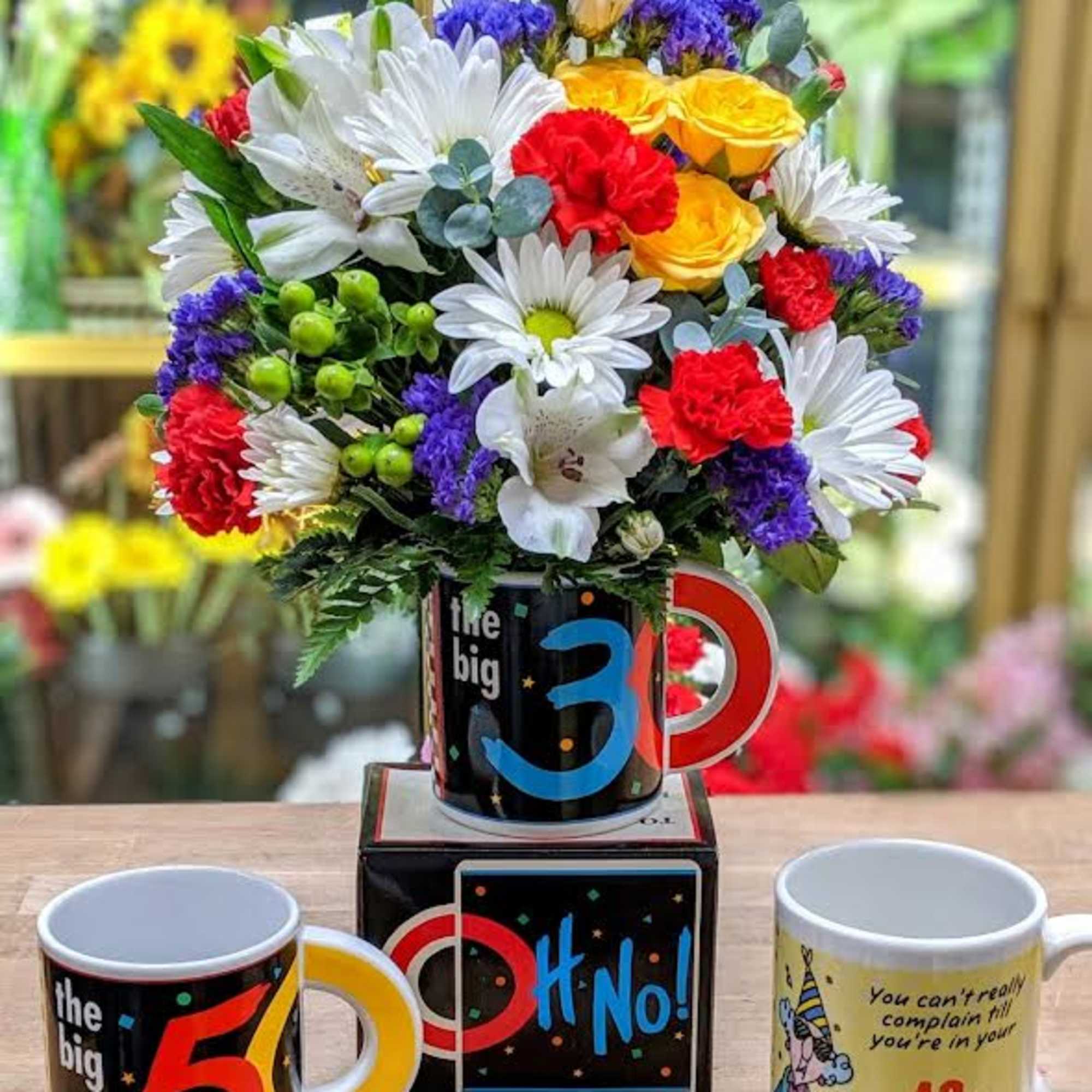 Colorful mixed flower arrangement in a mug with age-themed gift mugs