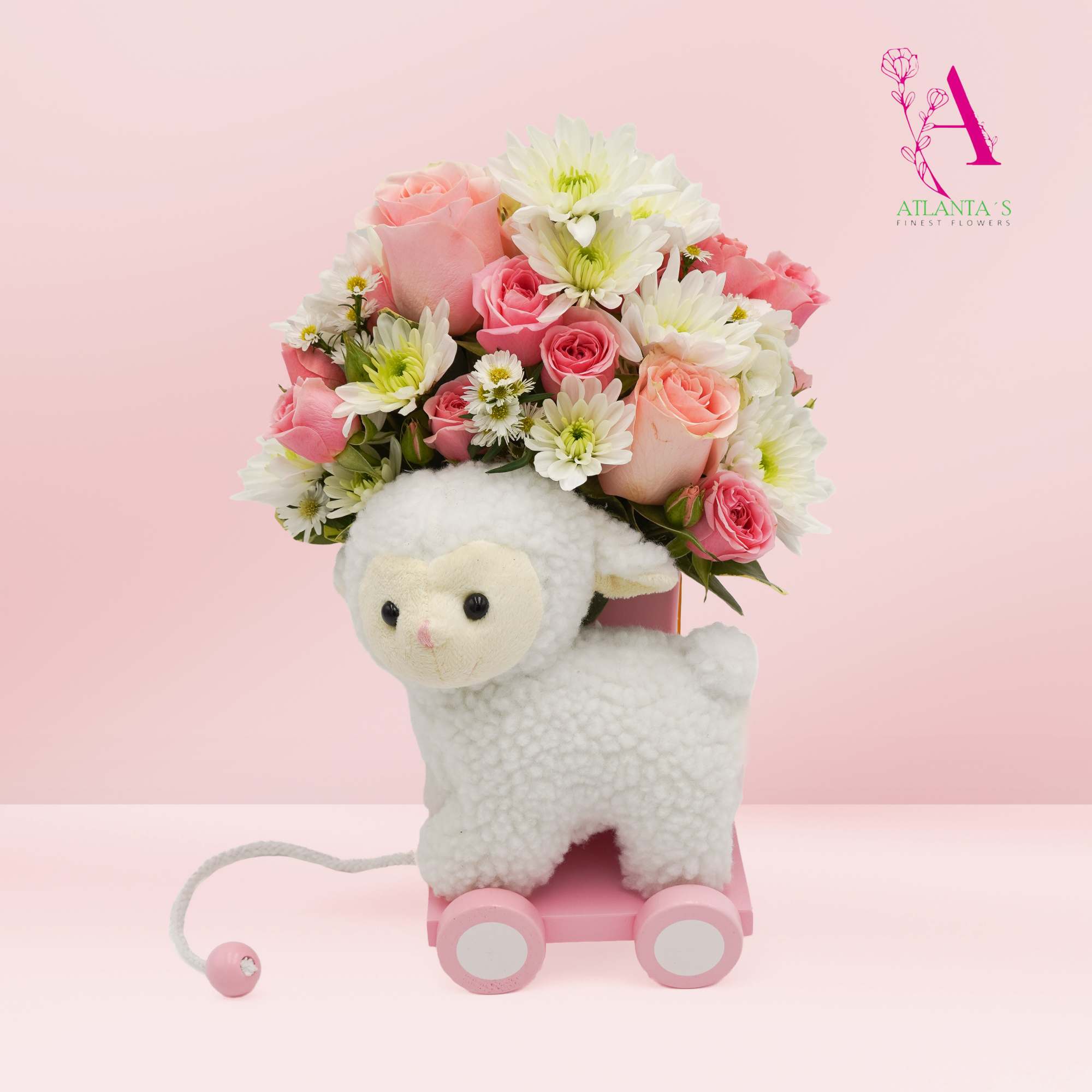 Pink and white flower arrangement with a plush lamb on a small pink cart