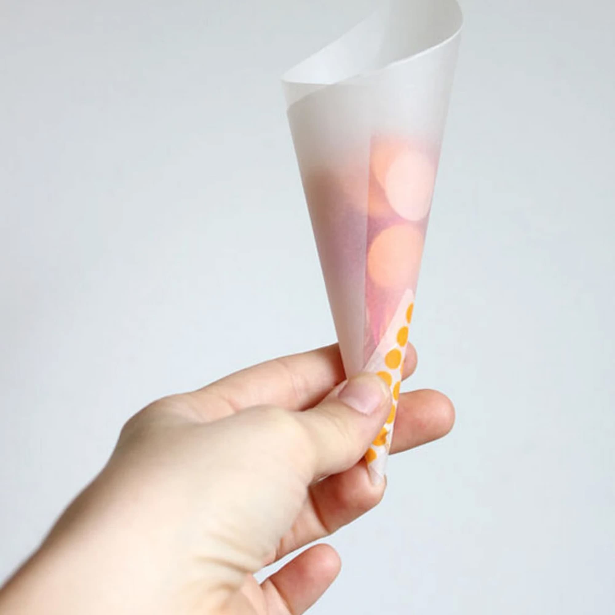 Hand holding a small white paper cone with a floral print