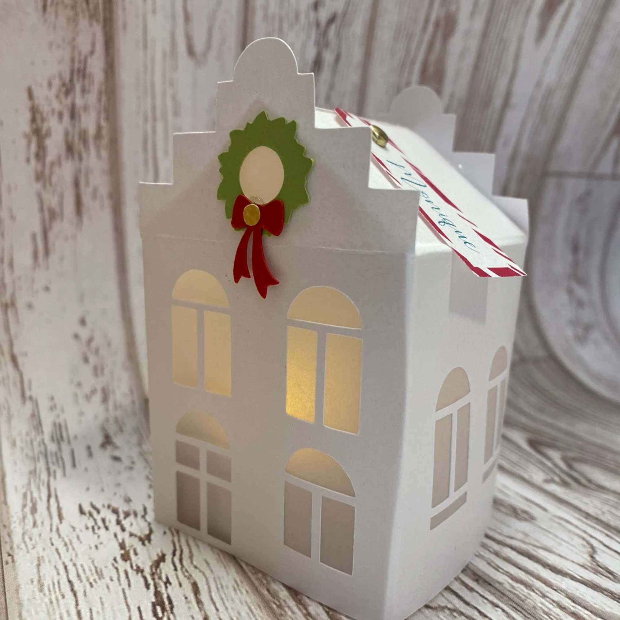 White paper house-shaped gift box with a holiday wreath decoration