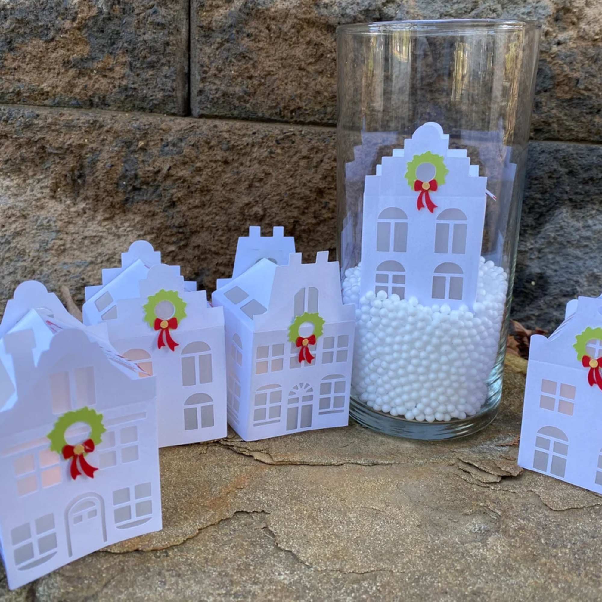 Paper house-shaped favor boxes and a glass cylinder with white filler