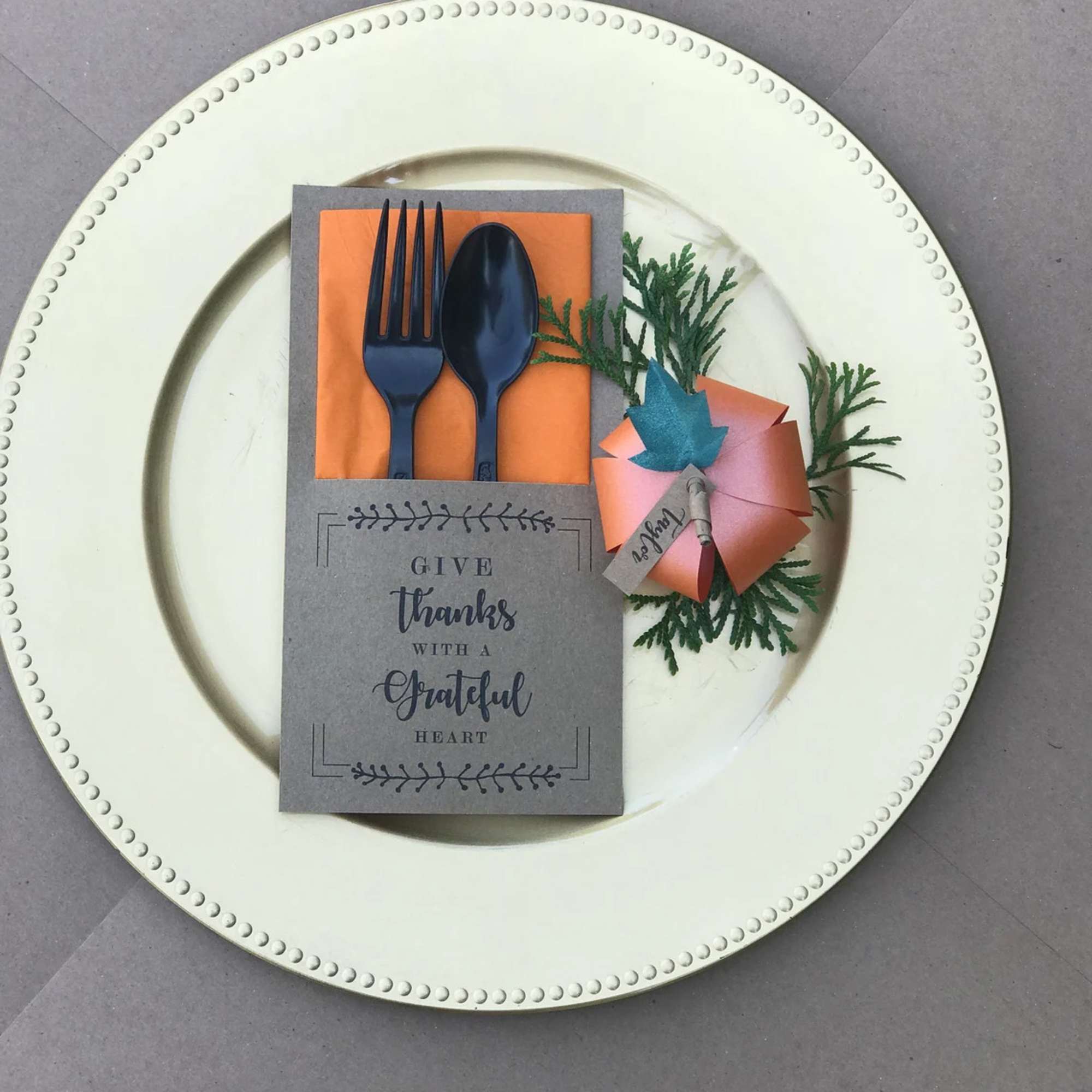 Thank-you place setting with a folded napkin, utensils, and a paper favor