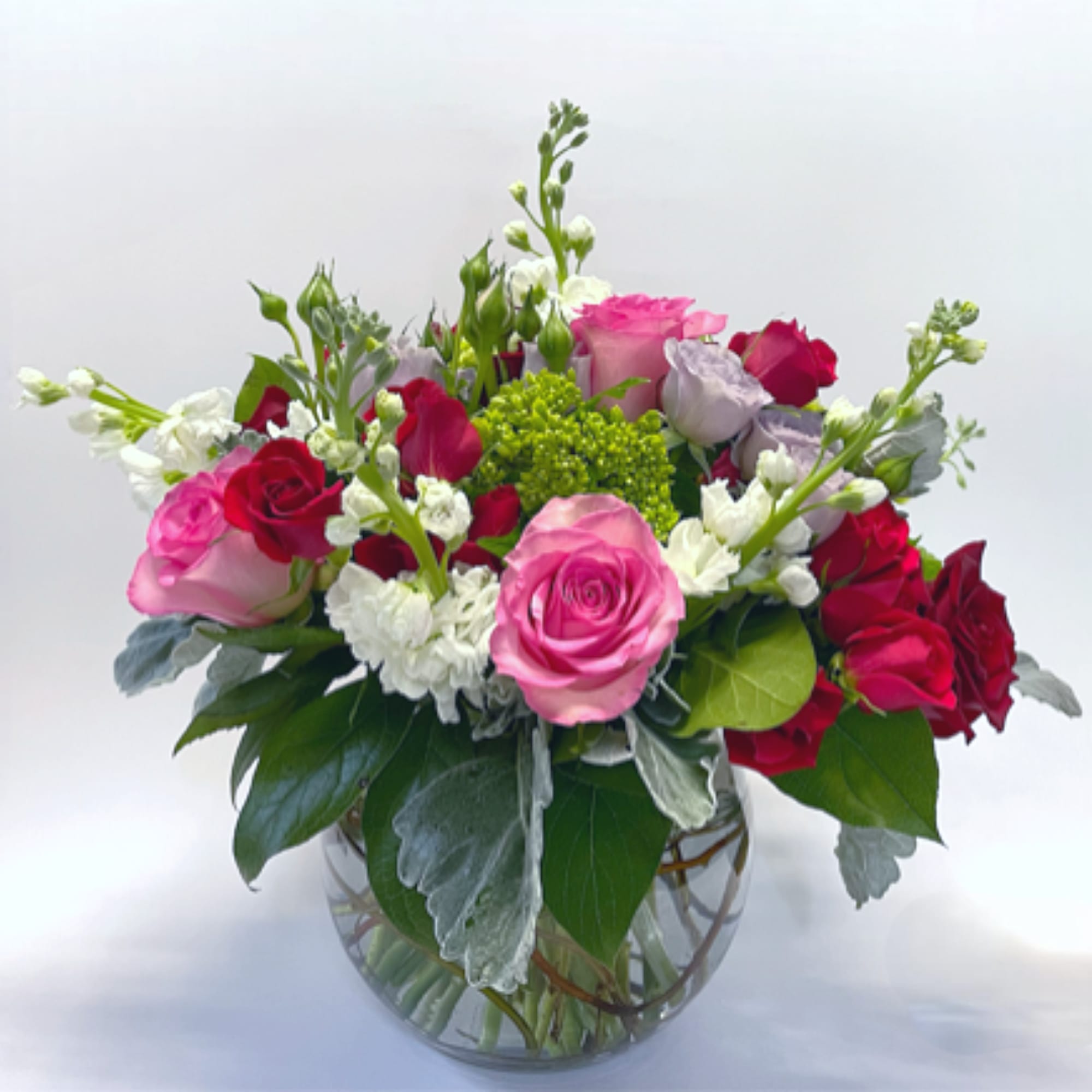 Mixed bouquet of pink, red, and white roses in a clear glass vase