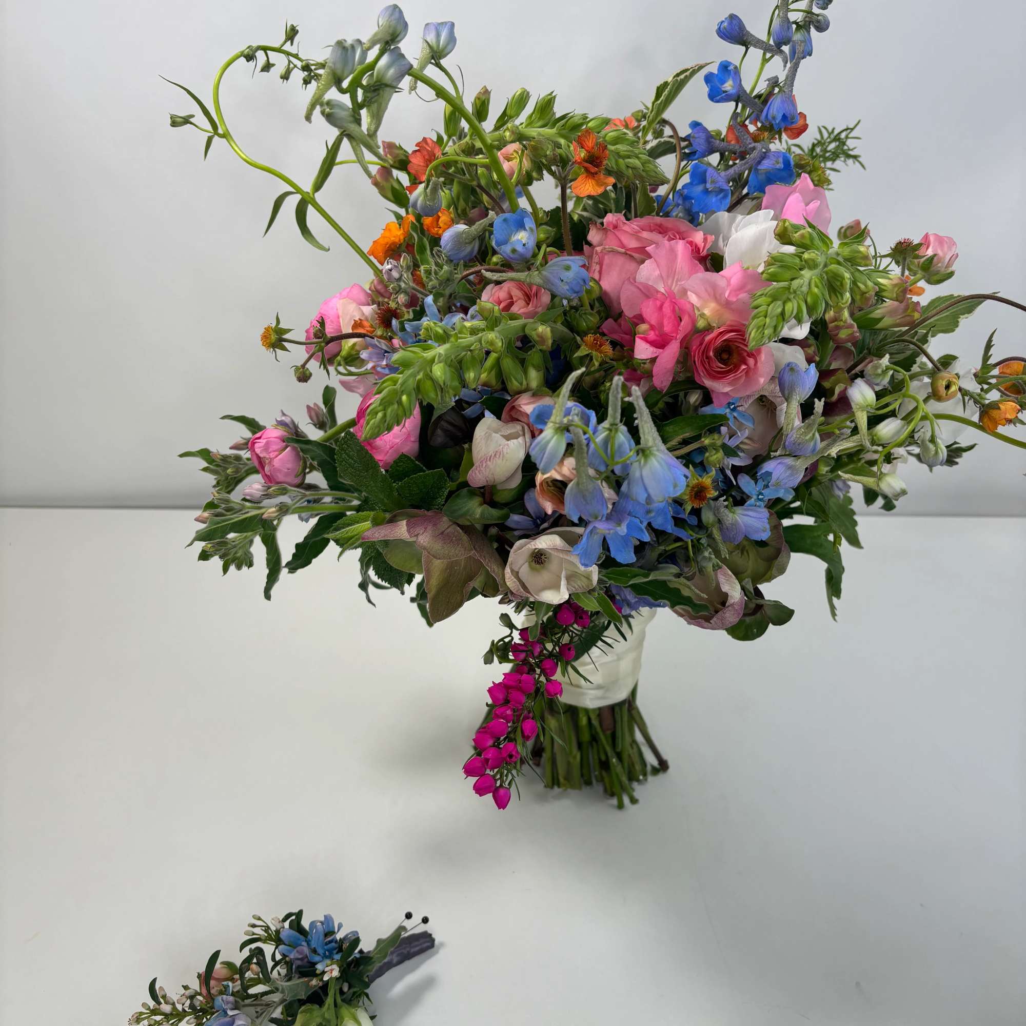 Loose bouquet of pink, blue, and white flowers with a wrapped stem bundle