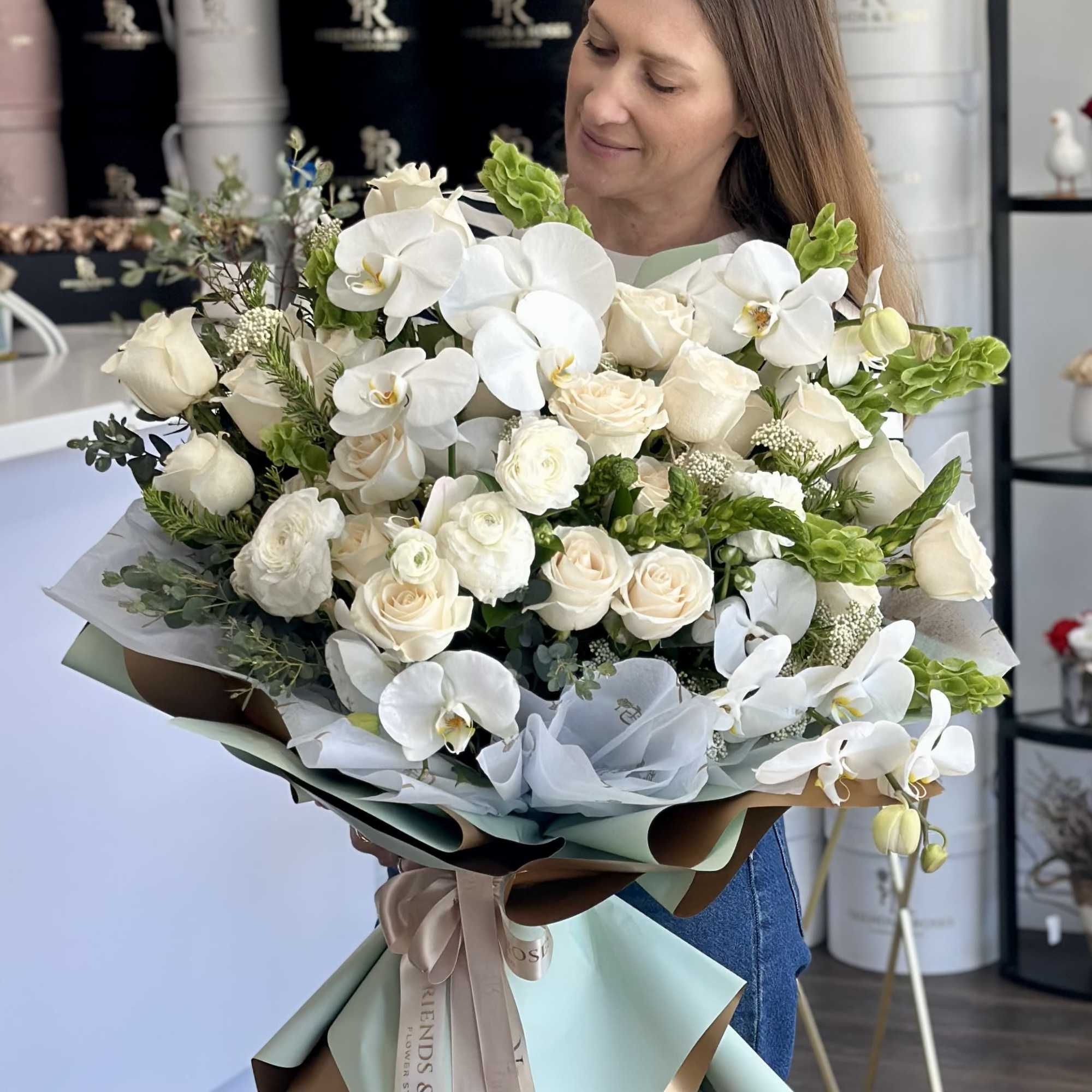 A luxurious and refined floral arrangement featuring pristine white orchids, soft ivory, photo 2 of 3