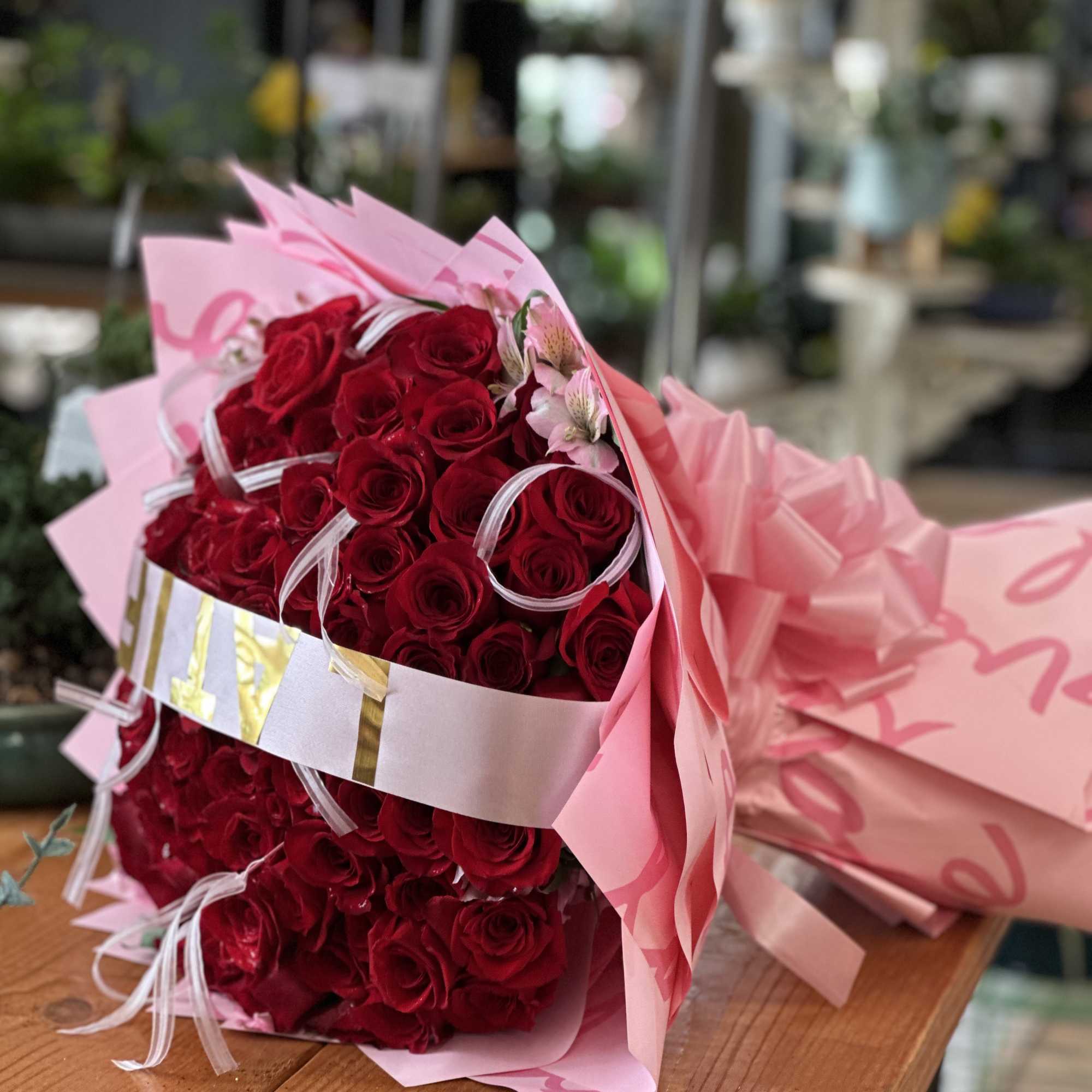 Bouquet of red roses wrapped in pink paper with ribbon