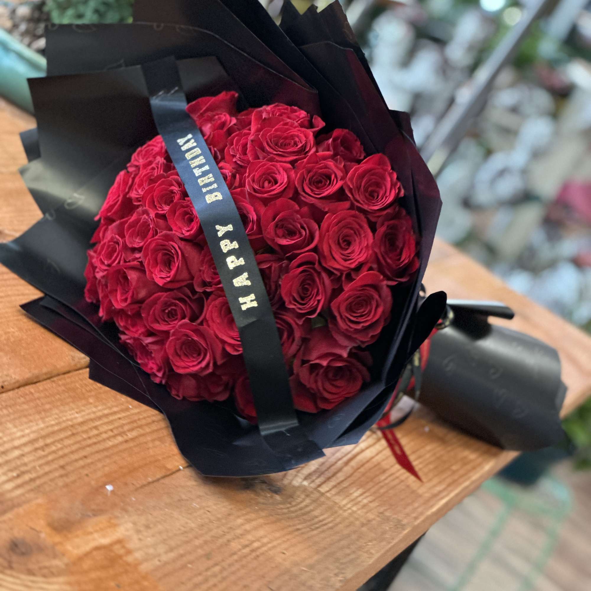Bouquet of red roses wrapped in black paper with a ribbon