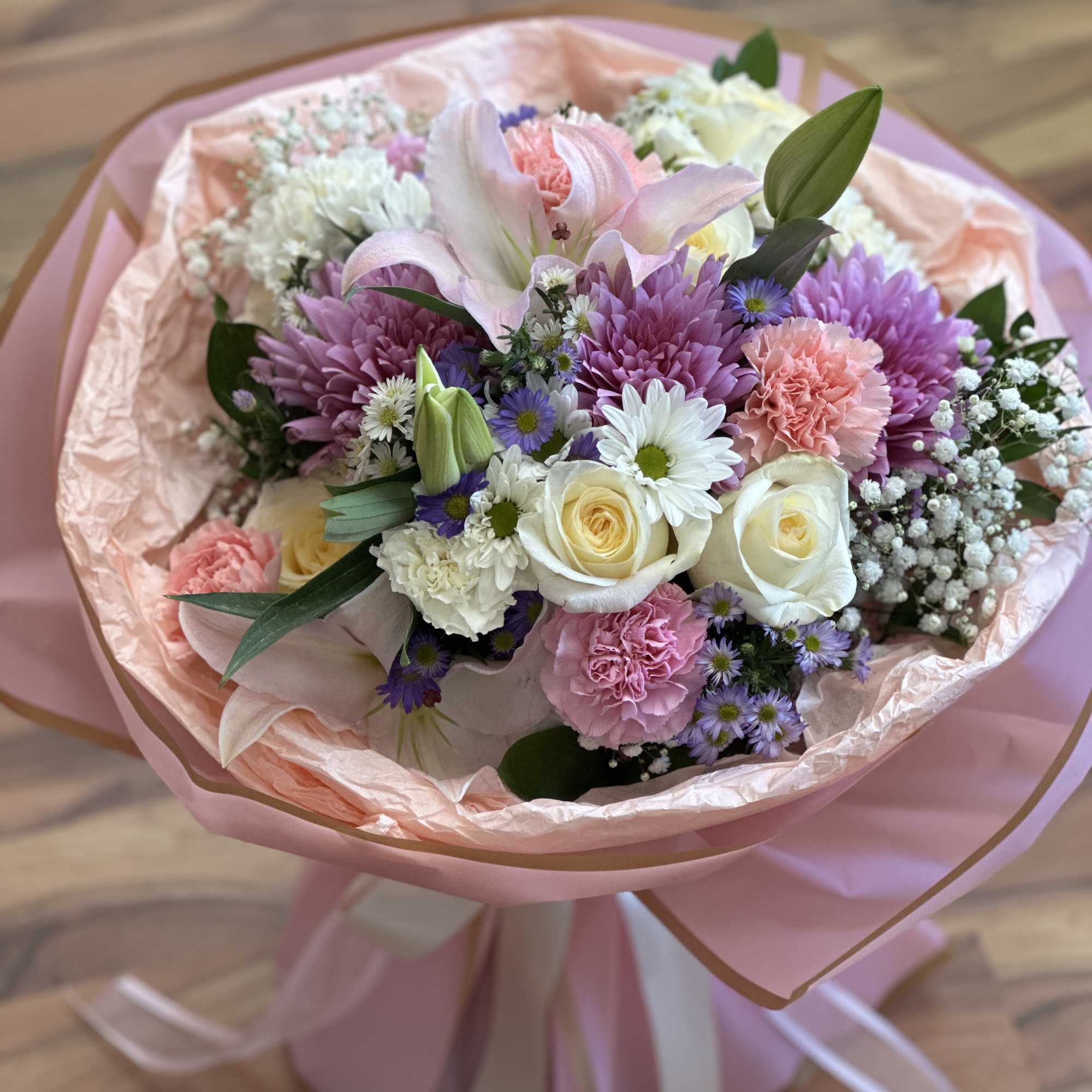 Pastel bouquet with lilies, roses, chrysanthemums, and carnations wrapped in pink paper