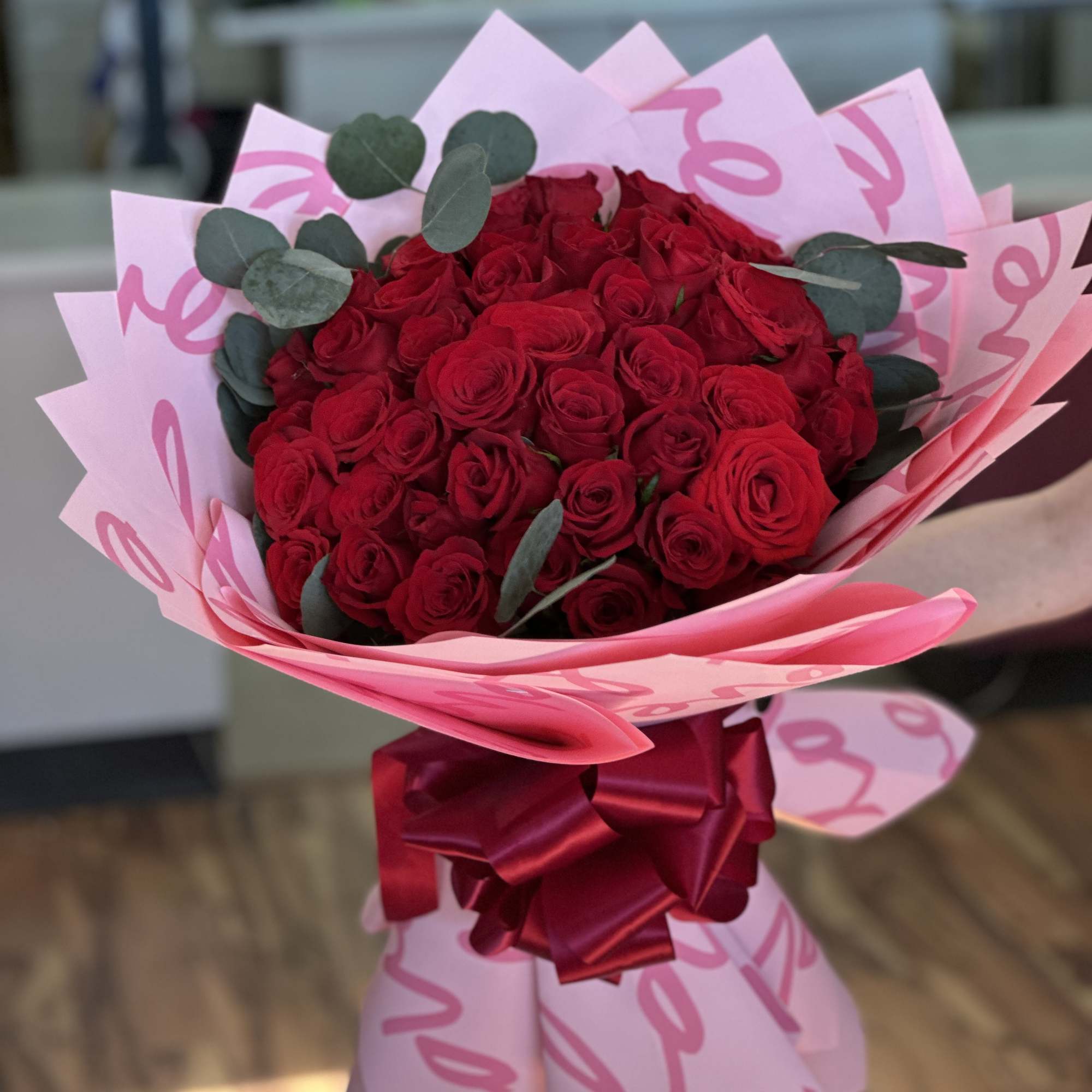 Bouquet of red roses wrapped in pink paper with a satin ribbon