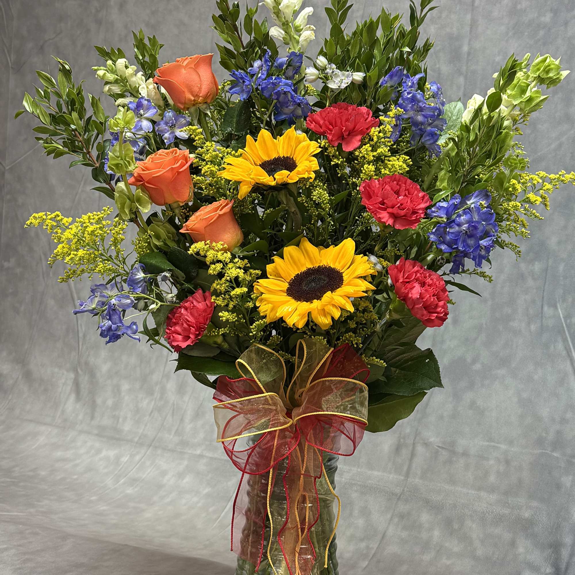 Mixed bouquet in a glass vase with sunflowers, roses, and carnations