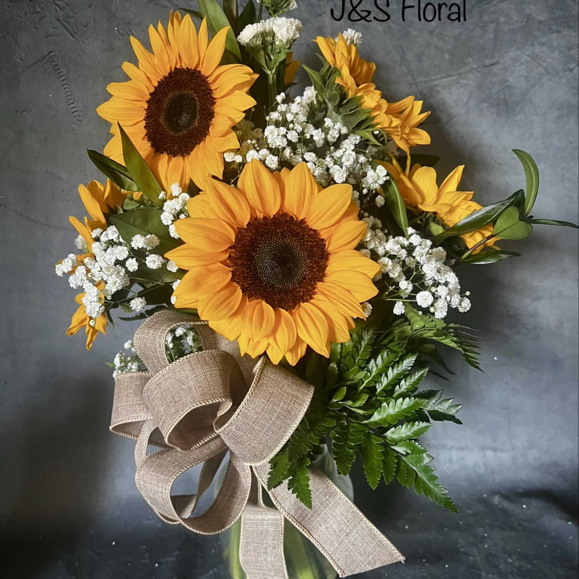 Sunflower bouquet in a glass vase with baby's breath and a burlap ribbon
