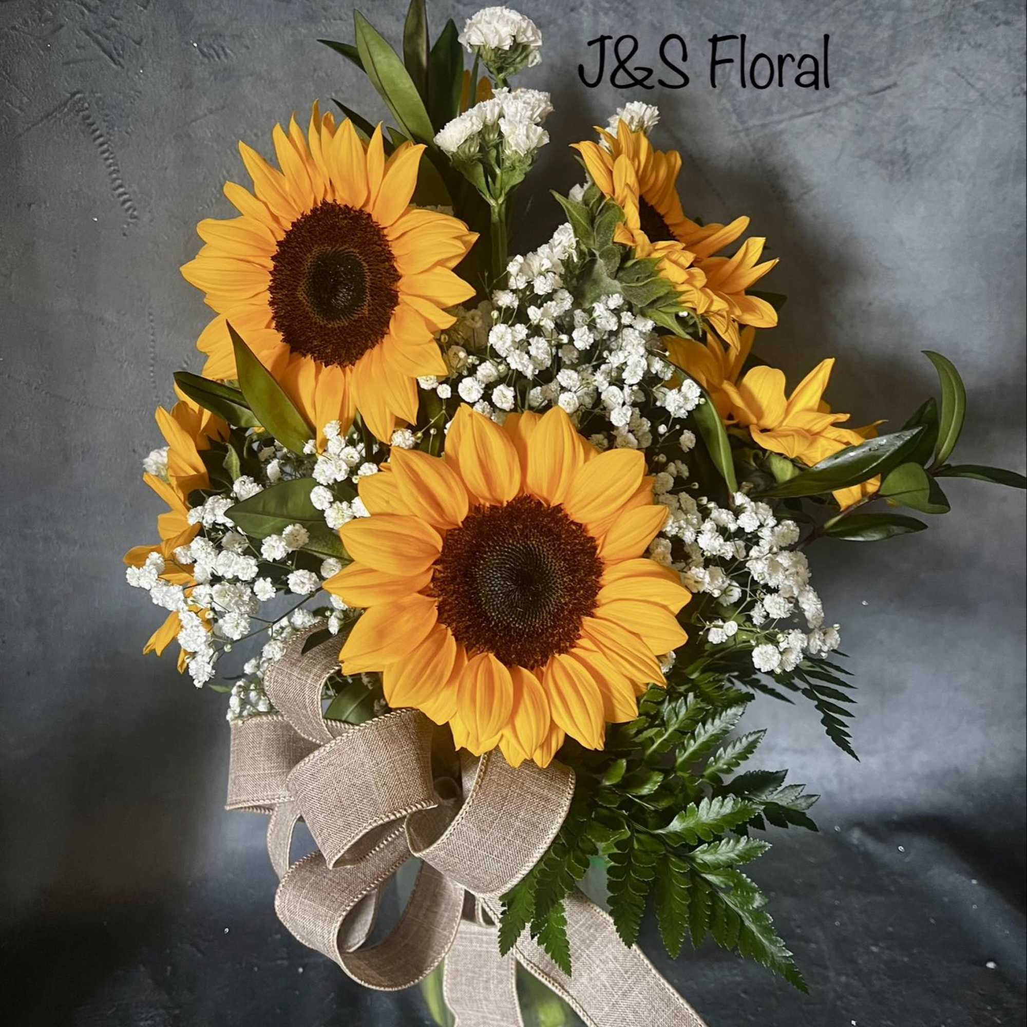Sunflower bouquet with white baby's breath in a glass vase and ribbon