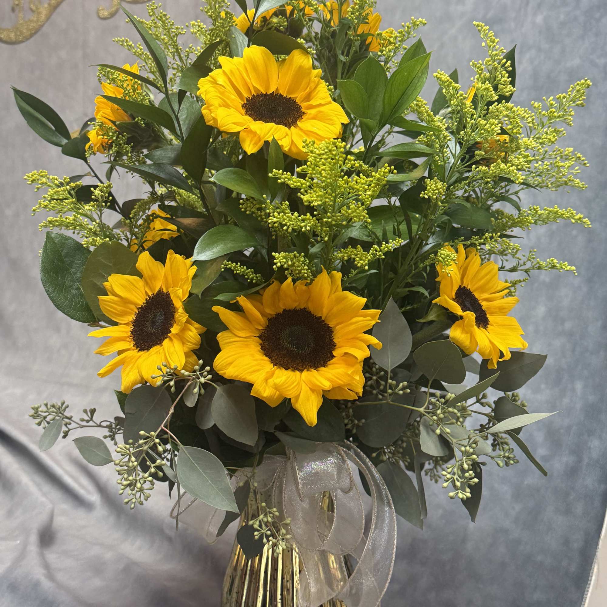 Sunflower arrangement in a gold vase with a sheer ribbon