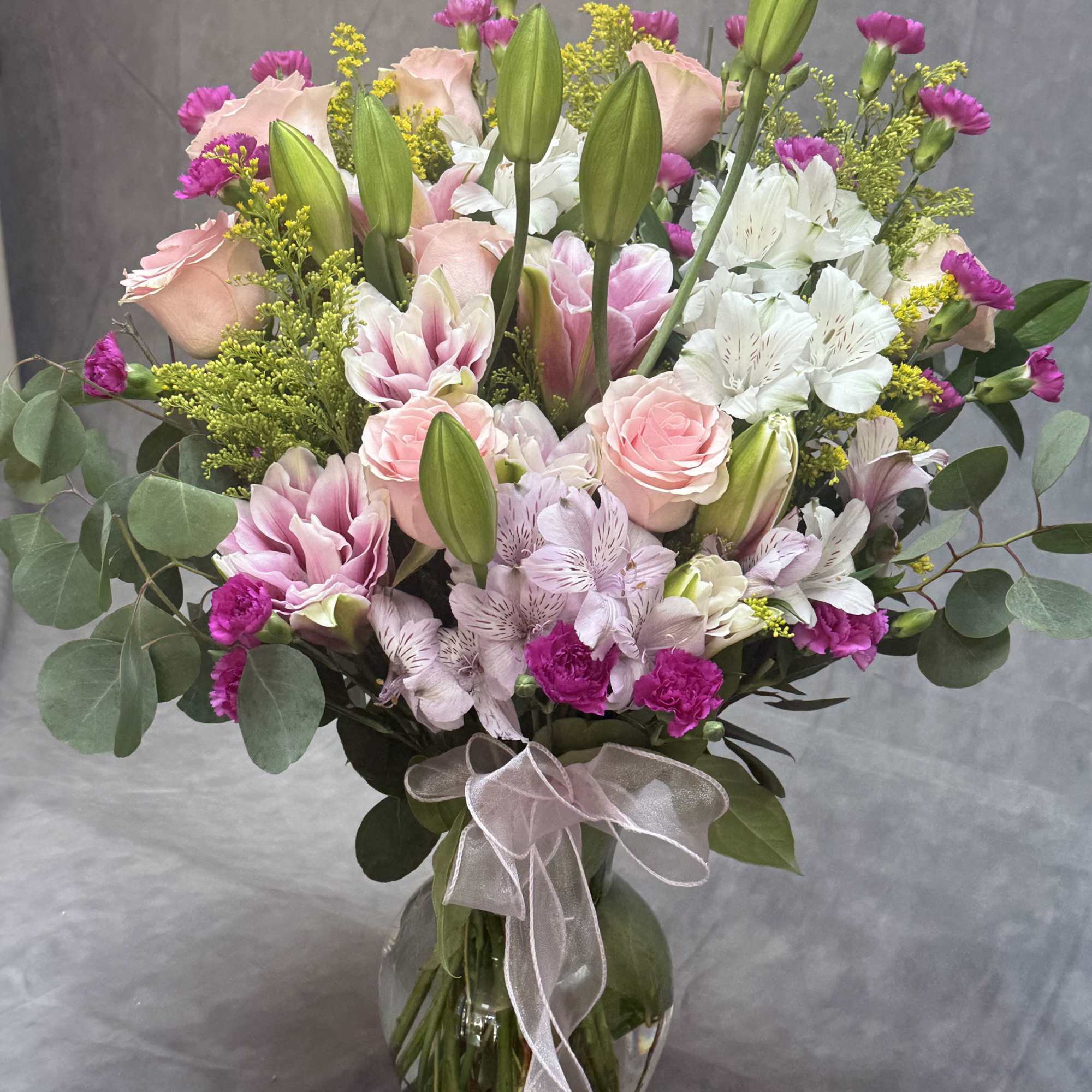 Pink and white bouquet in a glass vase with a ribbon