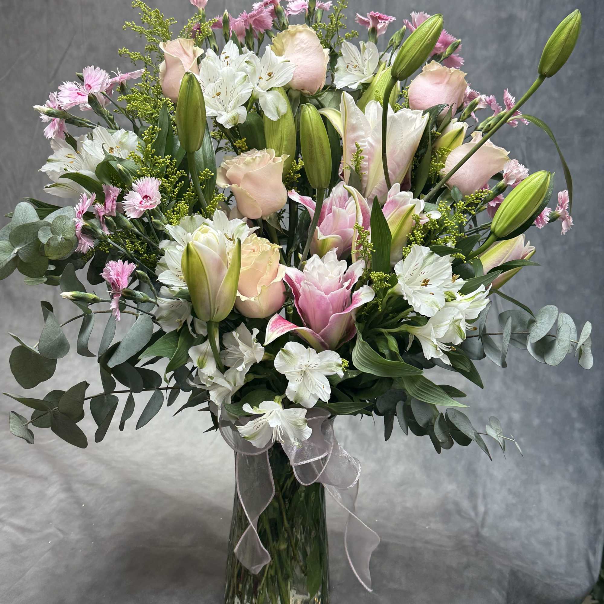 Pink and white bouquet with lilies and roses in a glass vase