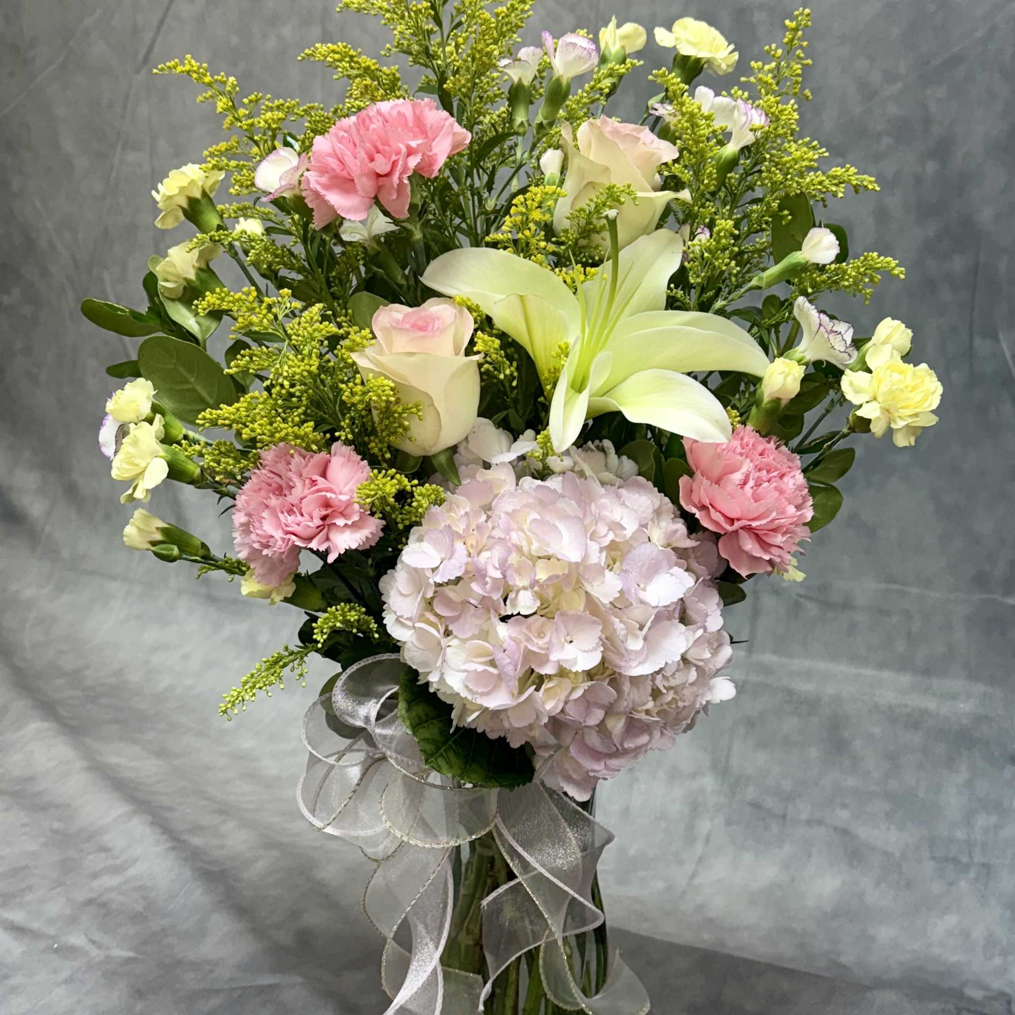 Bouquet of pink and white flowers in a glass vase with a ribbon