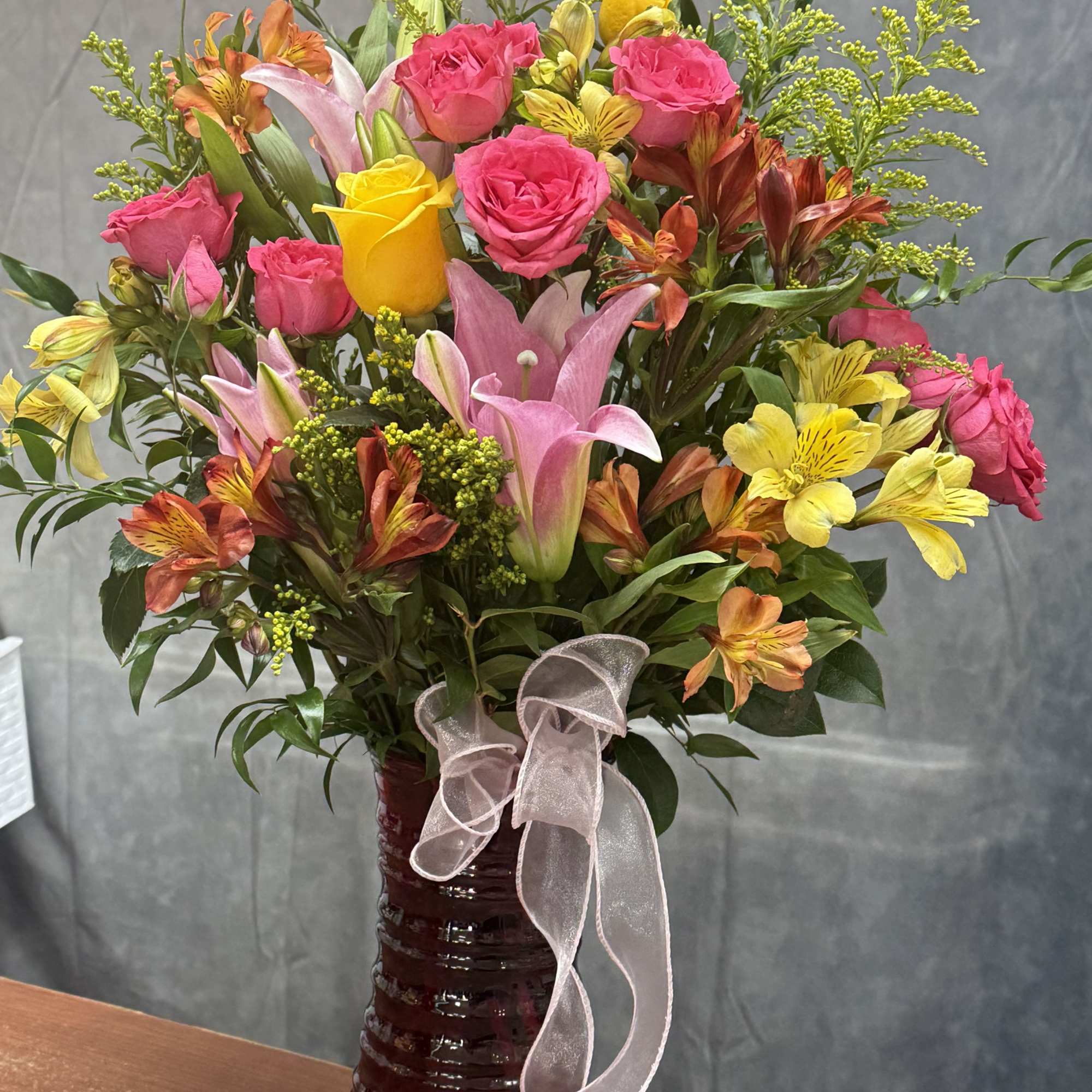 A bright and cheerful small vase featuring warm orange lilies, lively orange