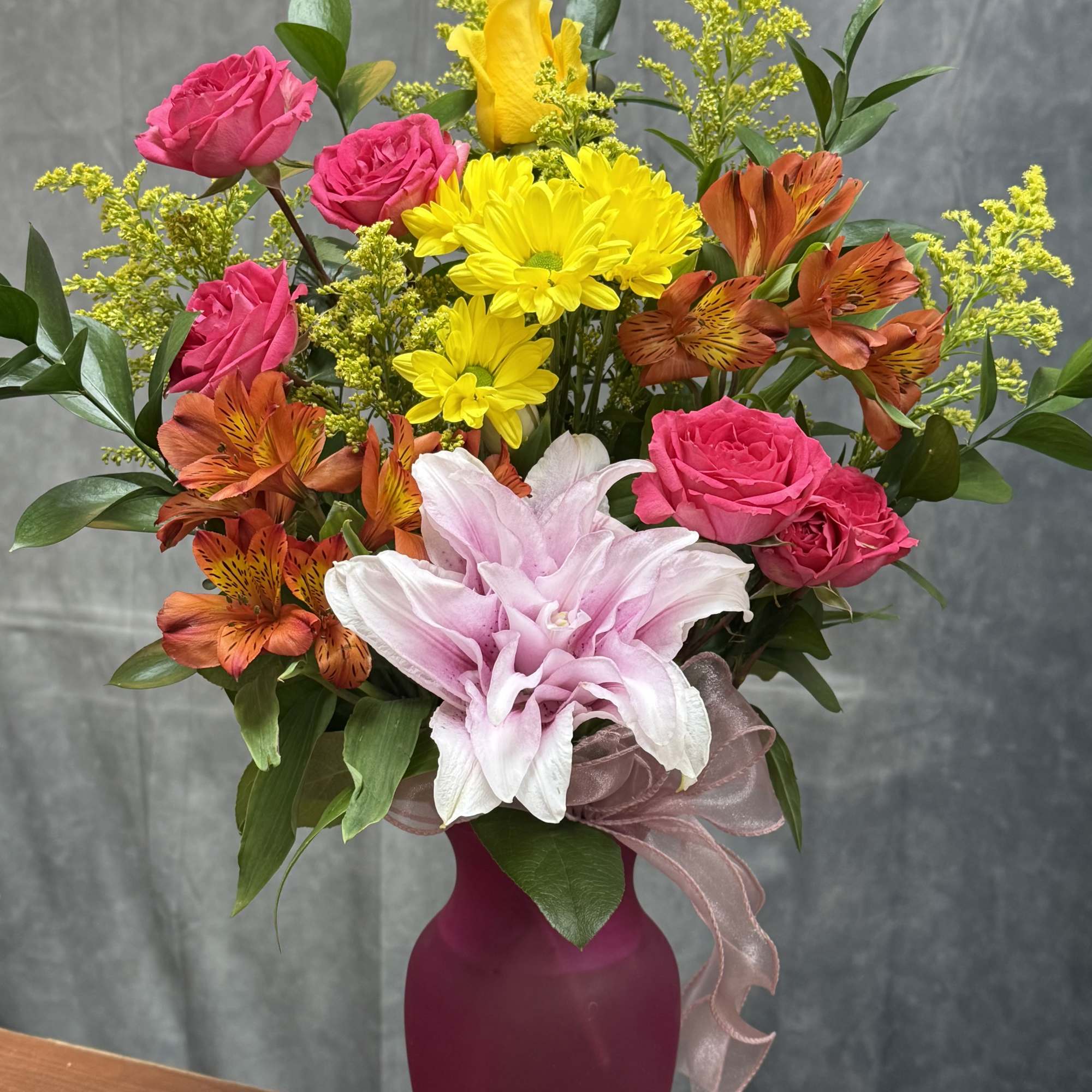 A bright and cheerful small vase featuring warm orange lilies, lively orange