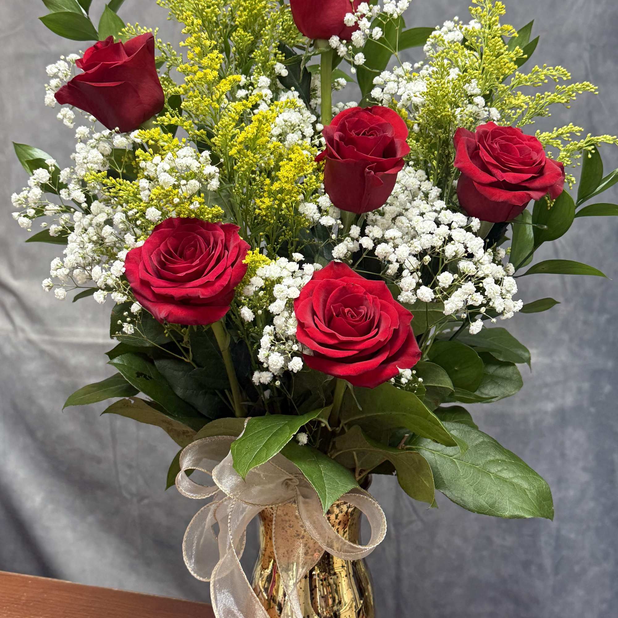 A charming mixed-rose arrangement featuring red roses accented with fresh greenery and