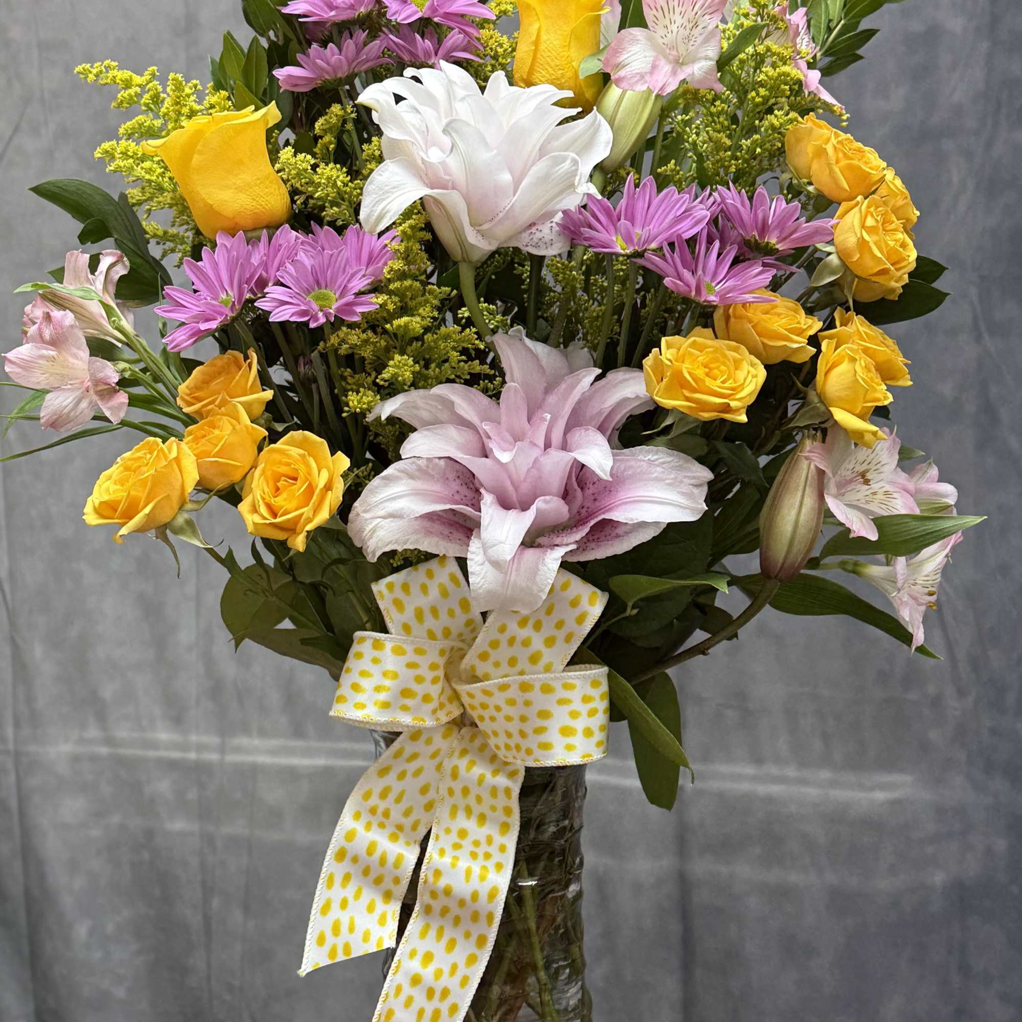 A charming mix of soft pink roses, delicate lavender buttons, sunny yellow