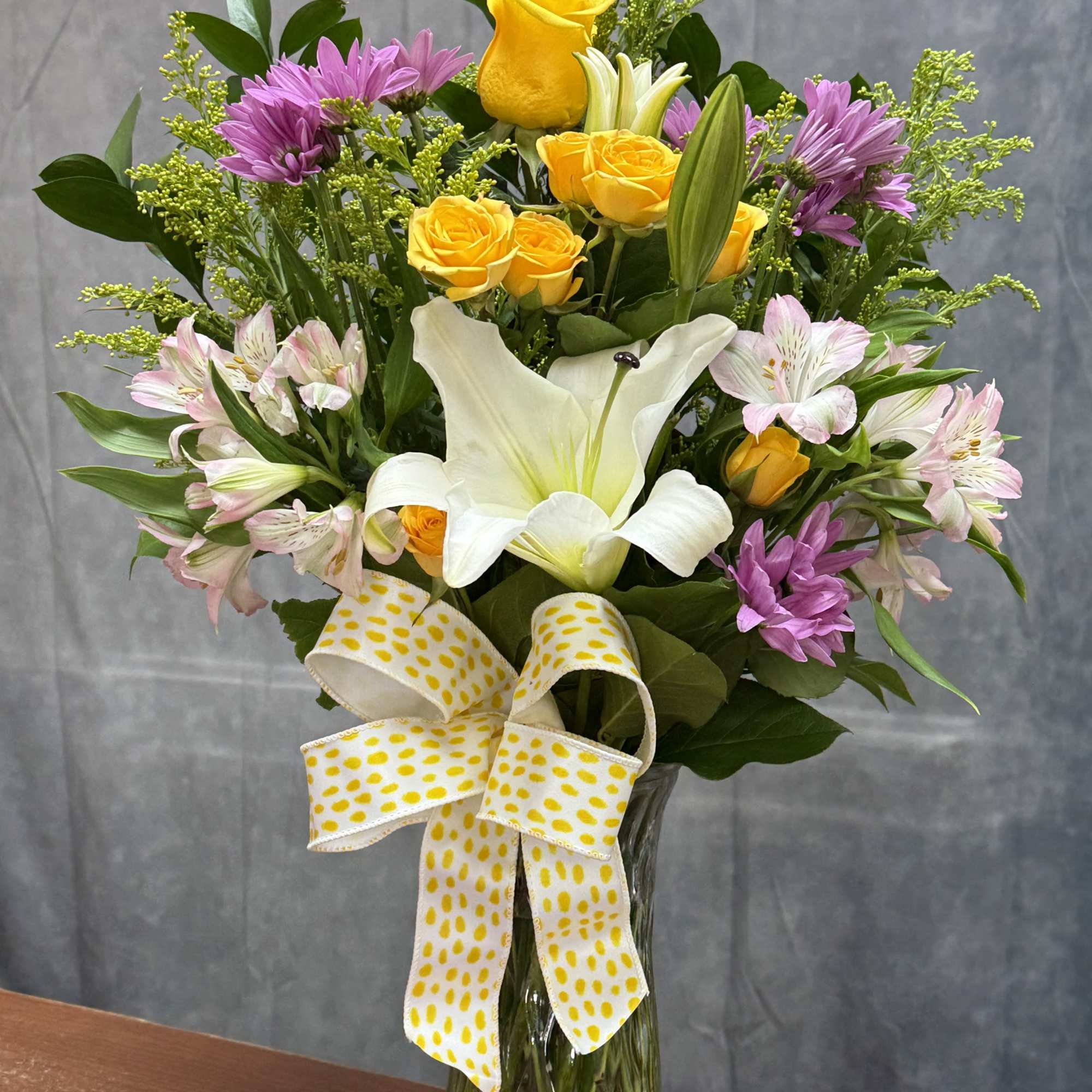 A charming mix of soft pink roses, delicate lavender buttons, sunny yellow