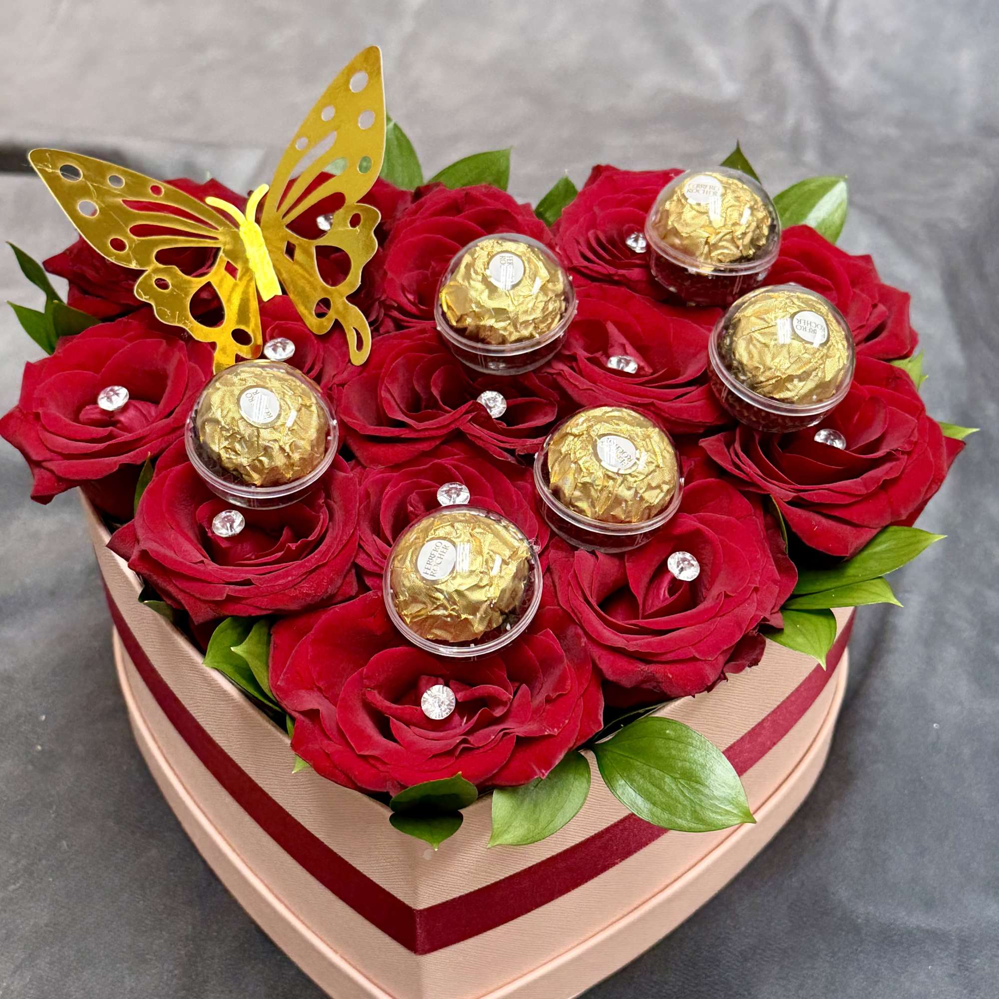 A luxurious heart-shaped box filled with 14 rich red roses, golden butterfly
