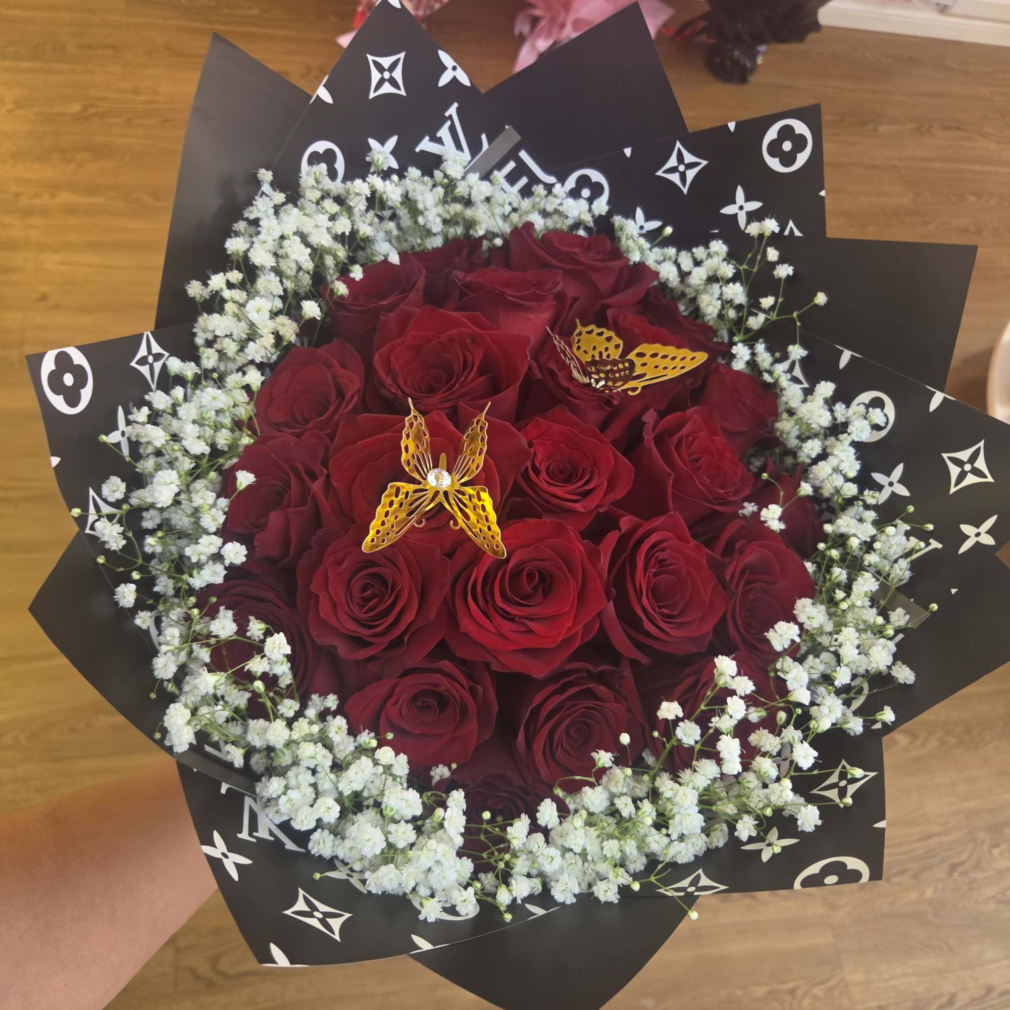 Bouquet of red roses with white baby's breath in black patterned wrap