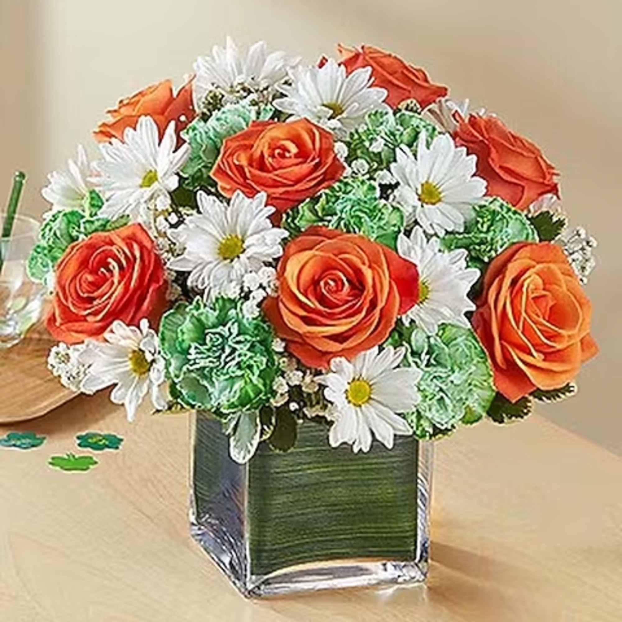  Compact arrangement of roses, carnations, and daisies in traditional orange, green