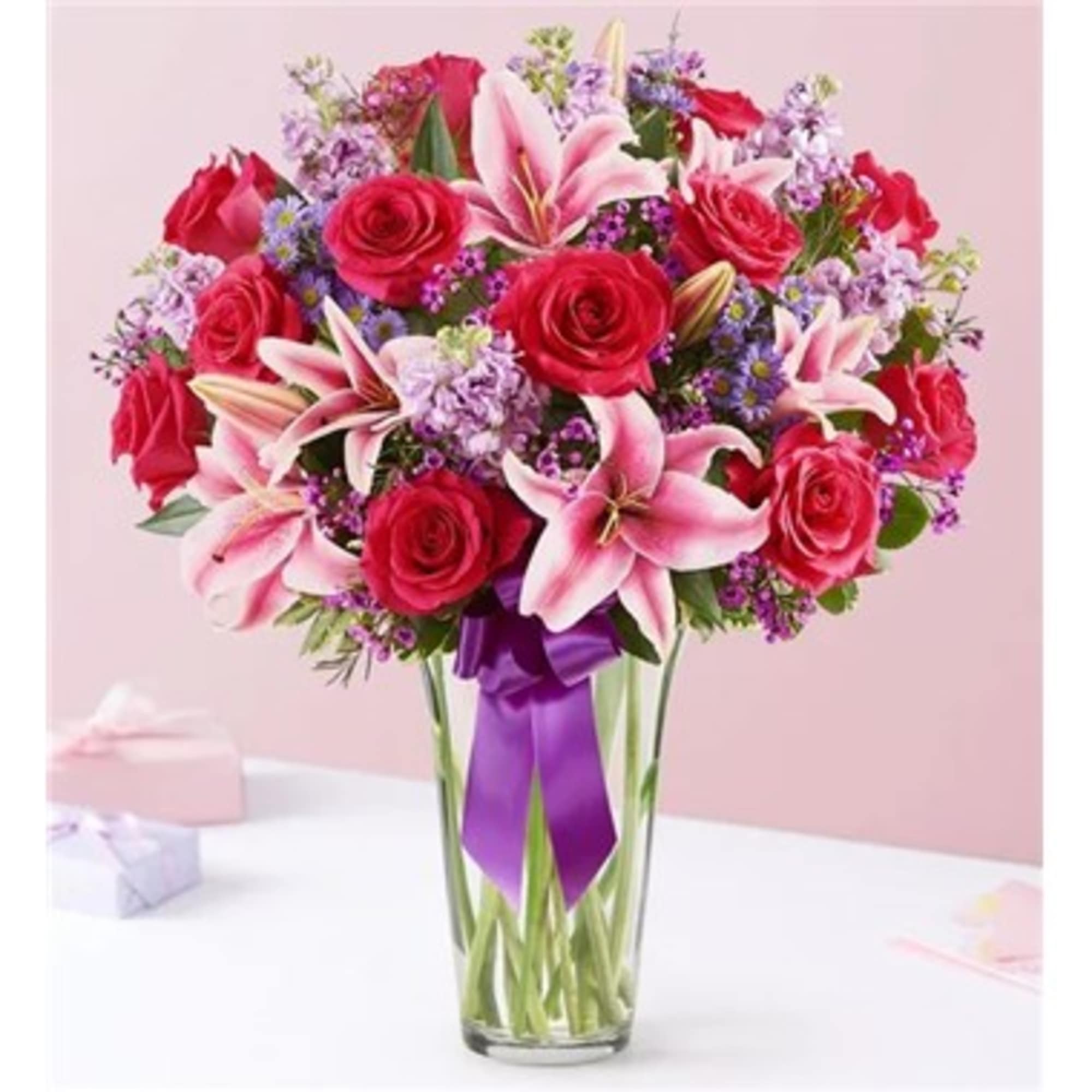 Bouquet of pink lilies and red roses in a clear glass vase