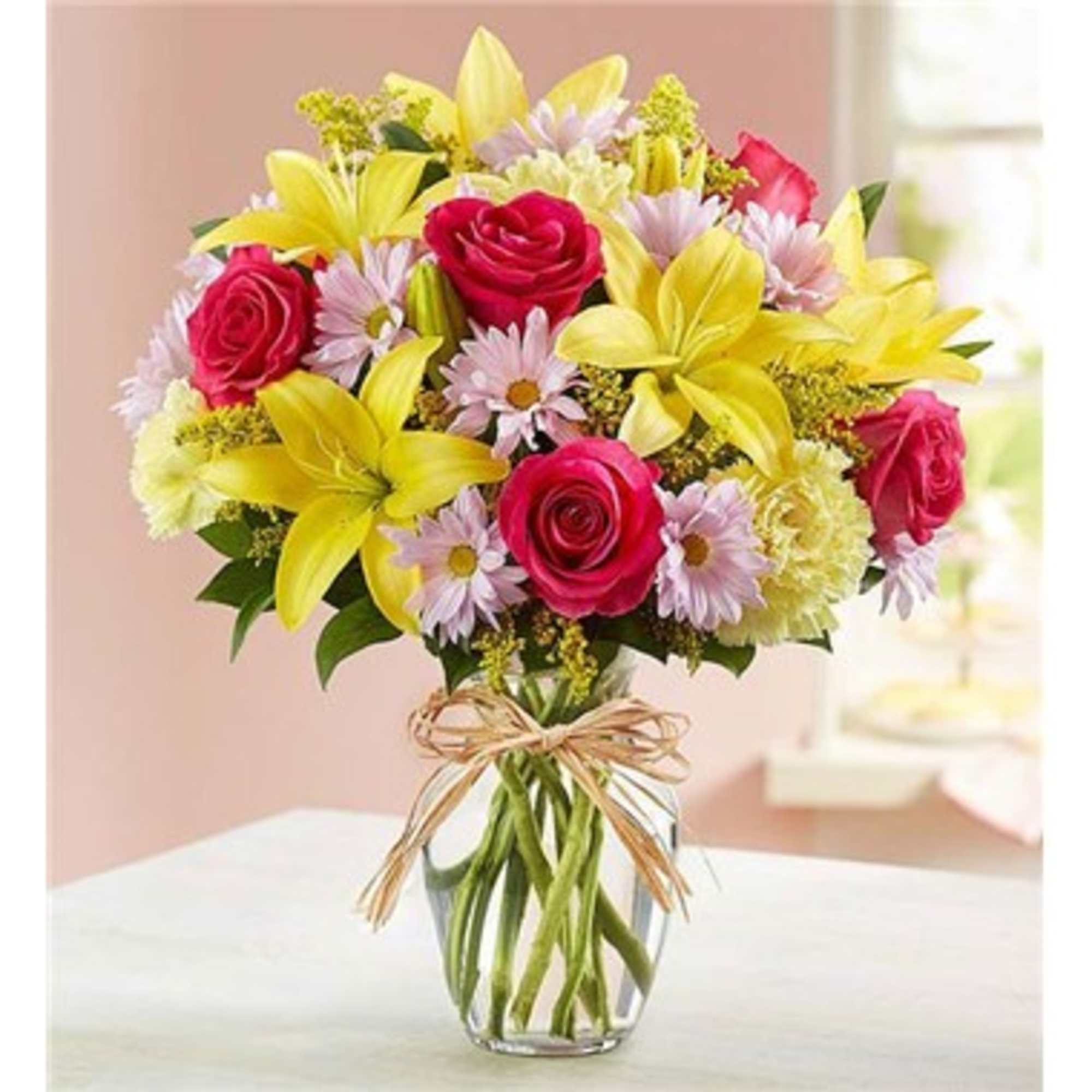 Bouquet of pink roses and yellow lilies in a clear glass vase