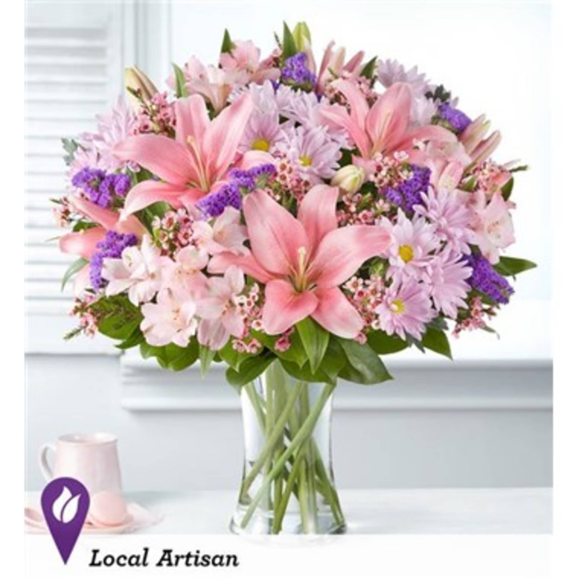 Pink lilies and lavender daisies arranged in a clear glass vase.
