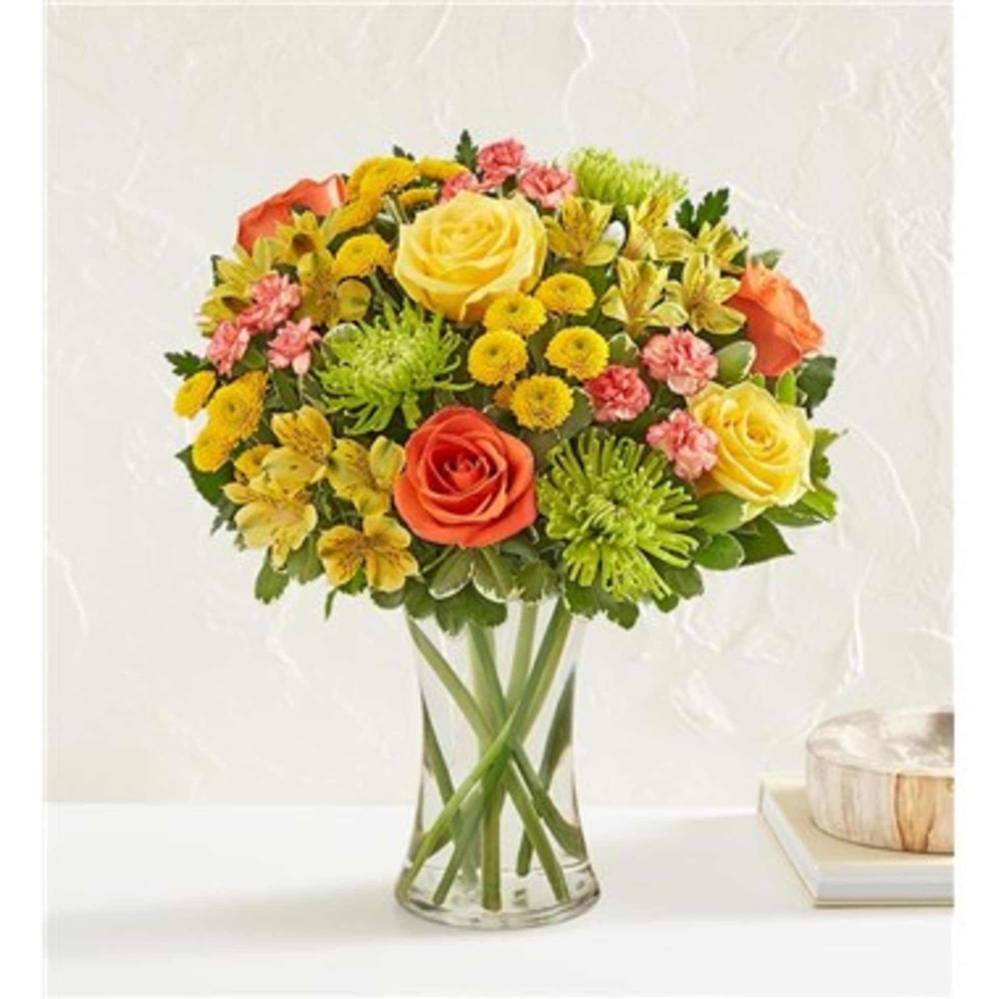 Mixed bouquet of yellow and orange flowers in a clear glass vase