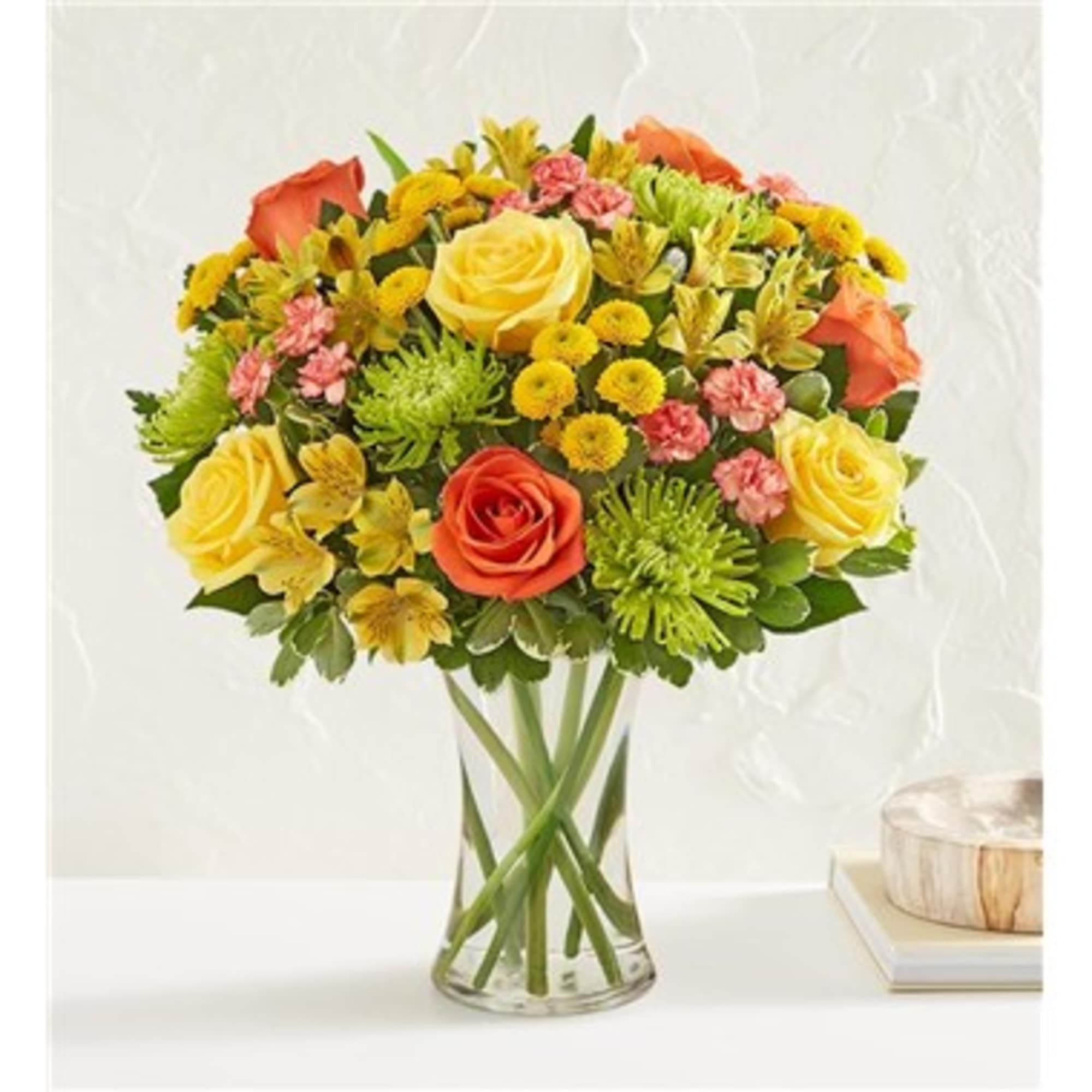 Mixed bouquet of yellow and orange flowers in a clear glass vase