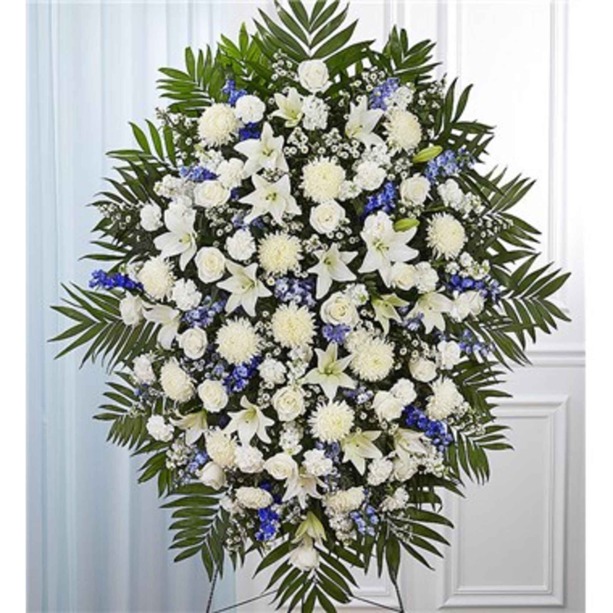 Large white and blue funeral spray with lilies and chrysanthemums
