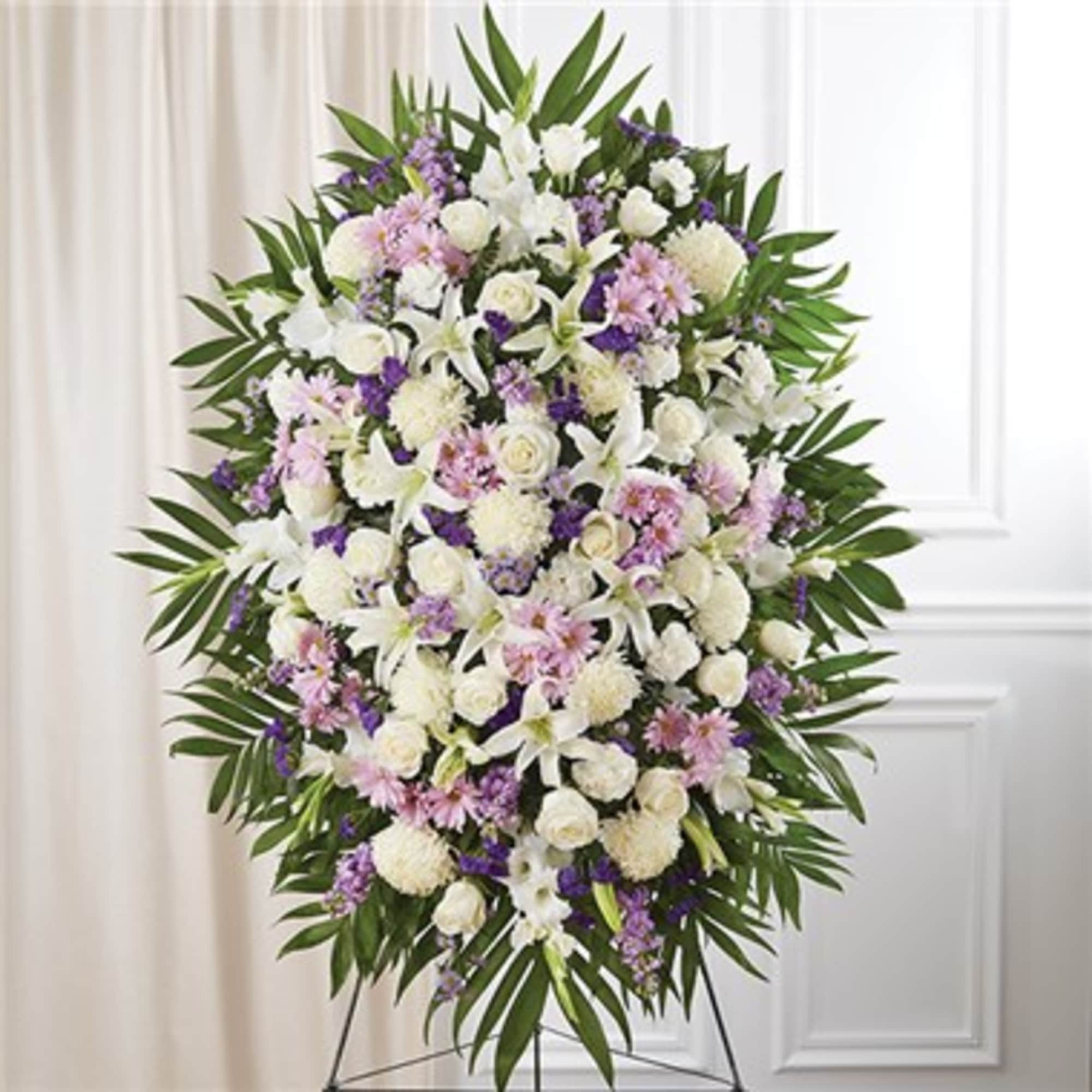 Standing funeral spray of white and lavender flowers on an easel