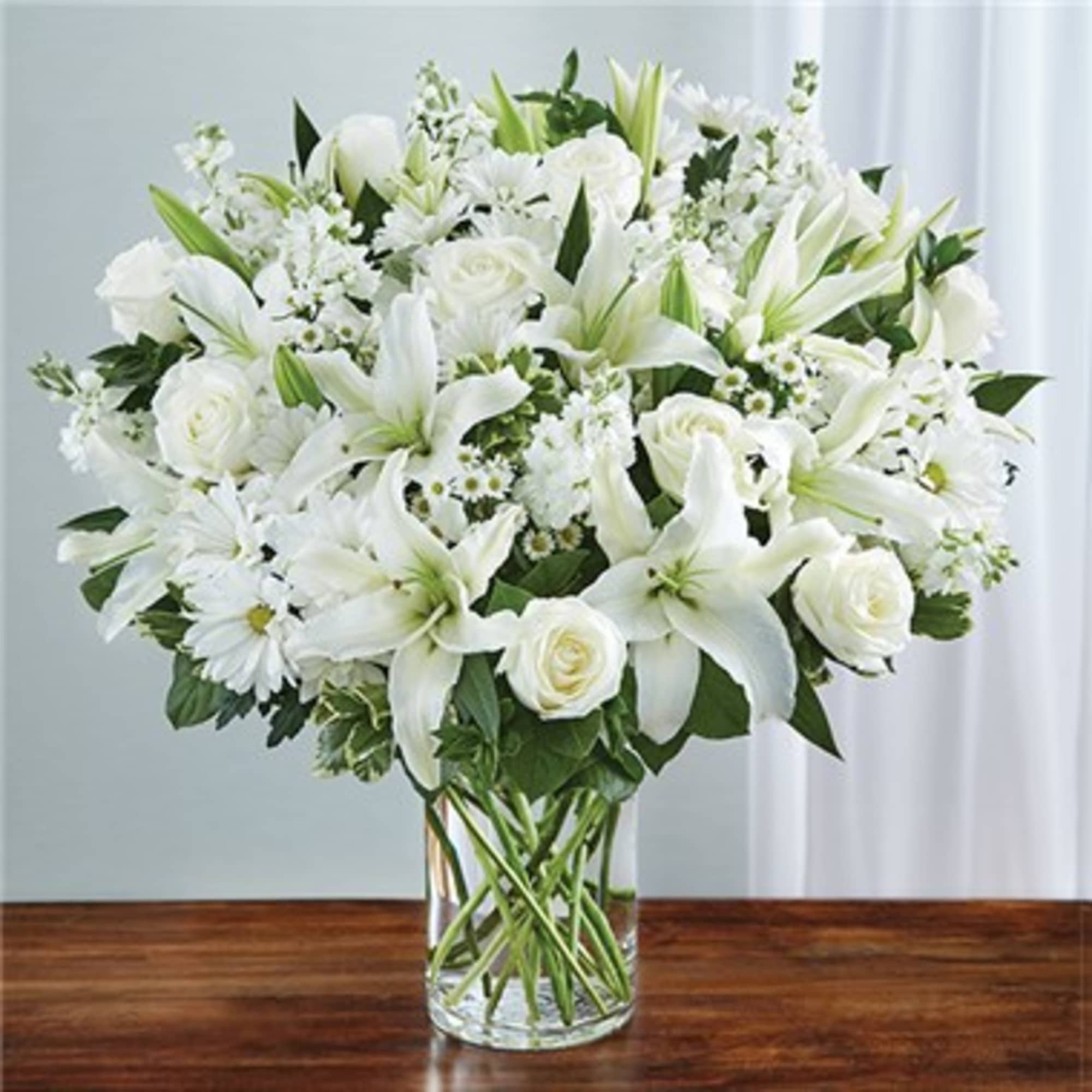 White lilies and roses arranged in a clear glass vase