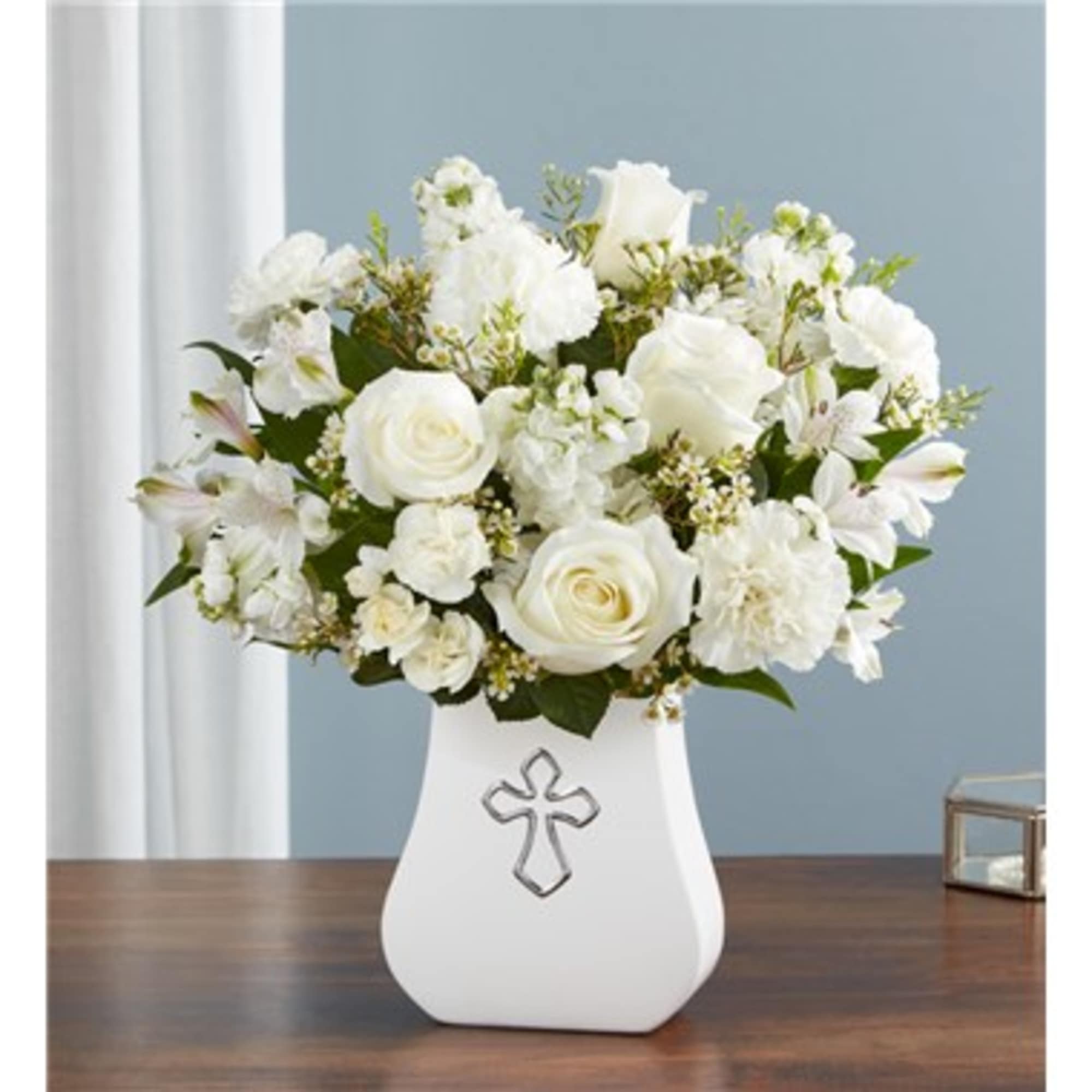 White floral arrangement in a white vase with a cross emblem