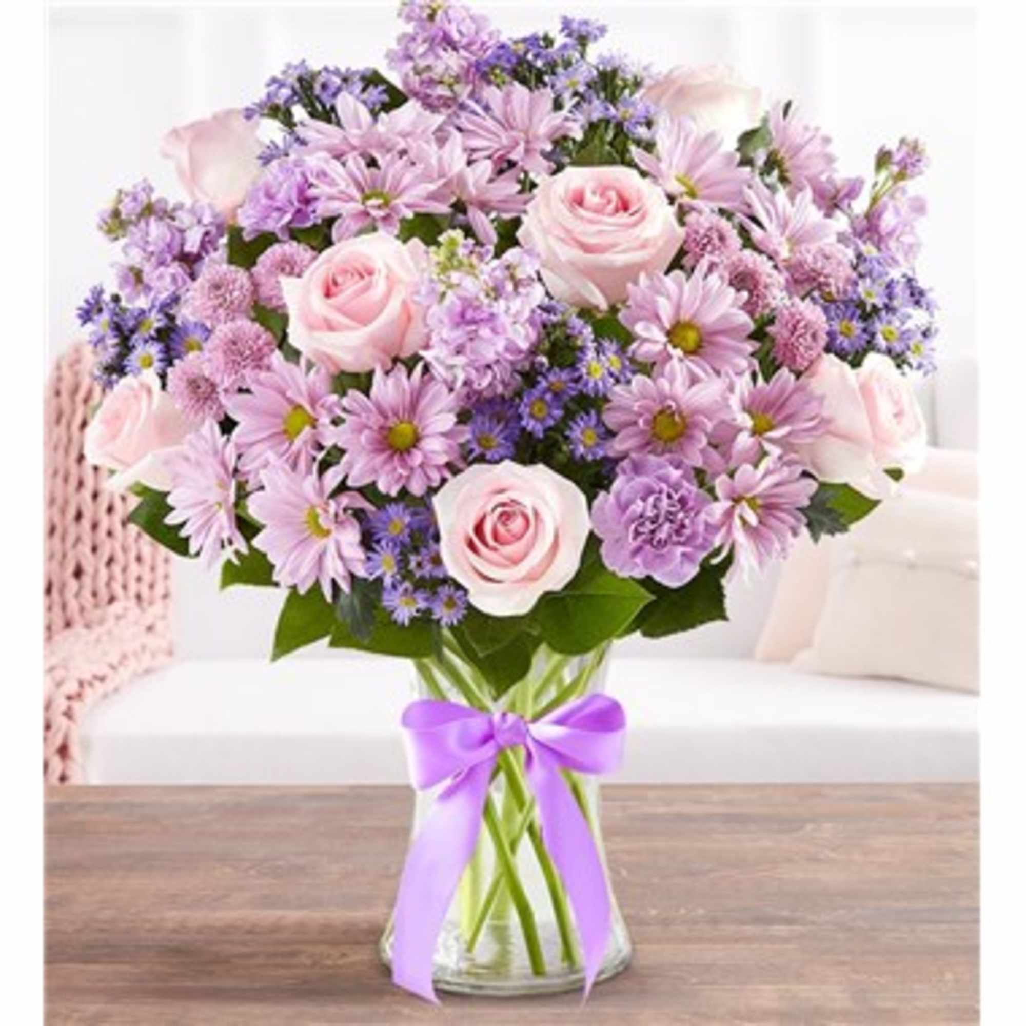 Pink and lavender bouquet in a clear glass vase with a purple ribbon