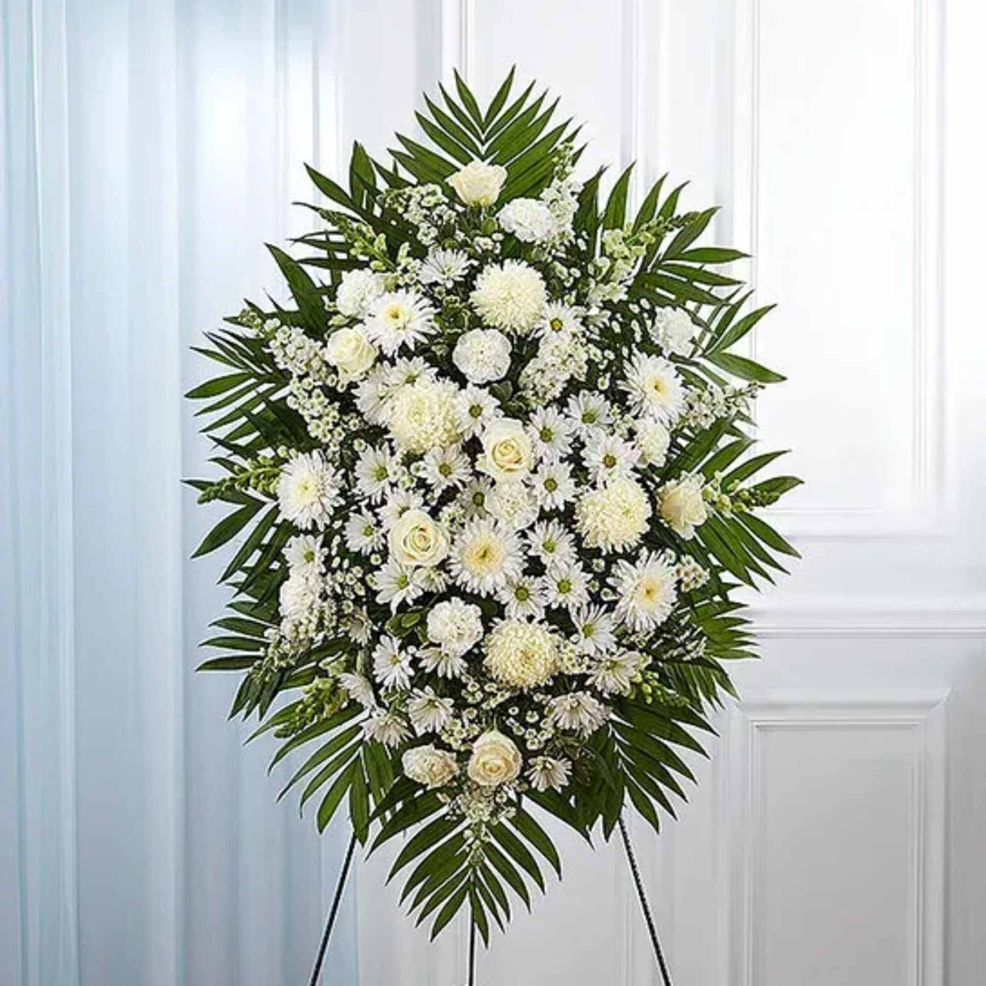 White funeral spray with daisies and roses on an easel