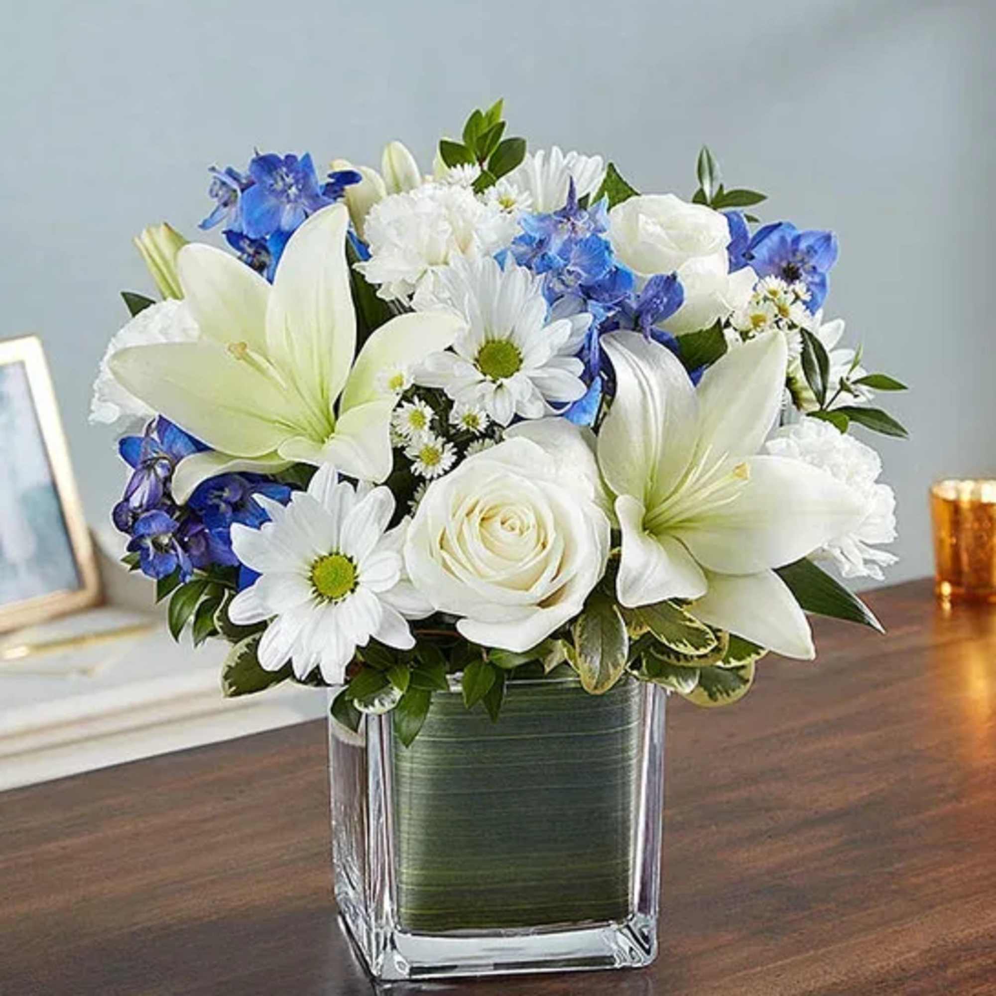 White and blue flower arrangement in a square glass vase