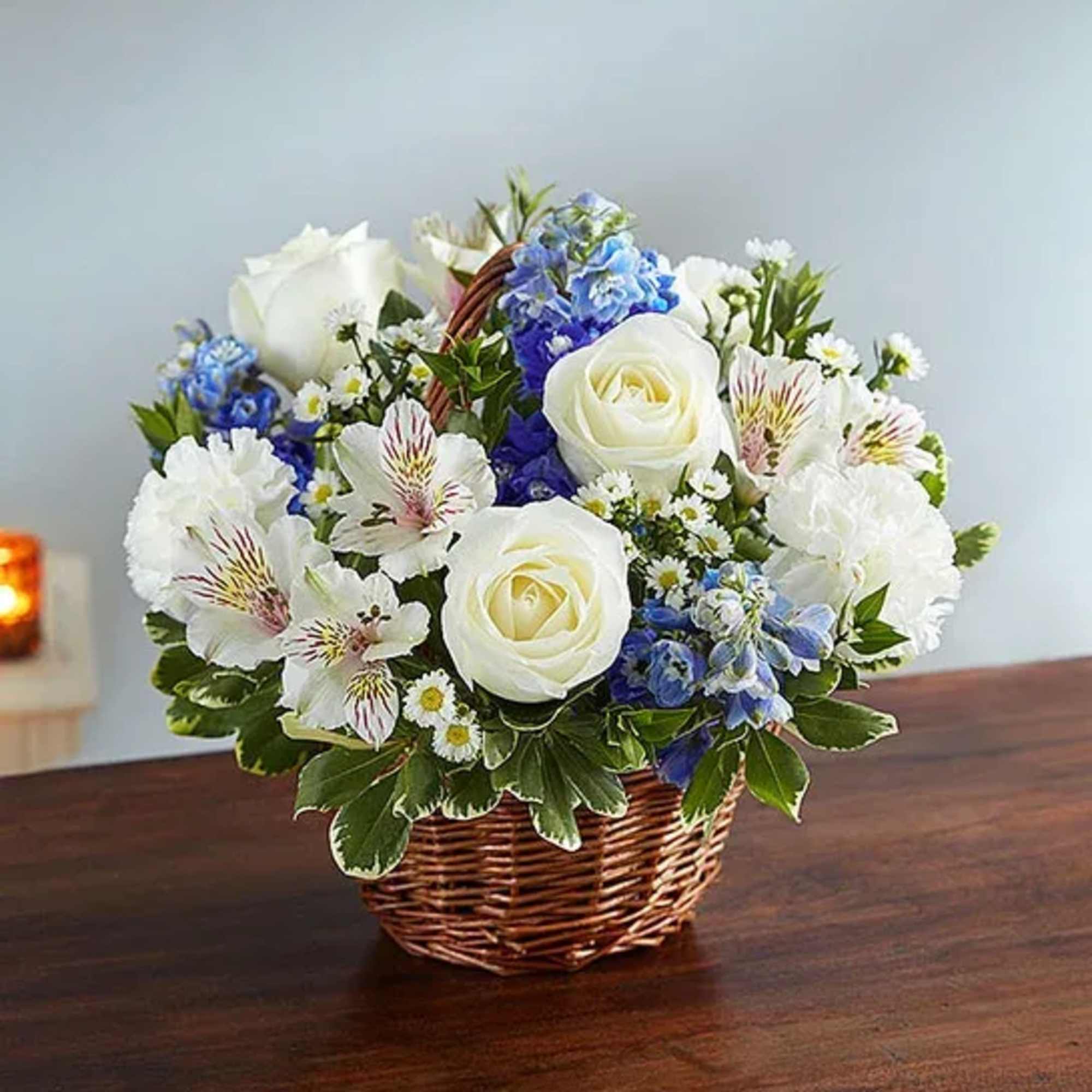 Basket of white roses and blue flowers on a table