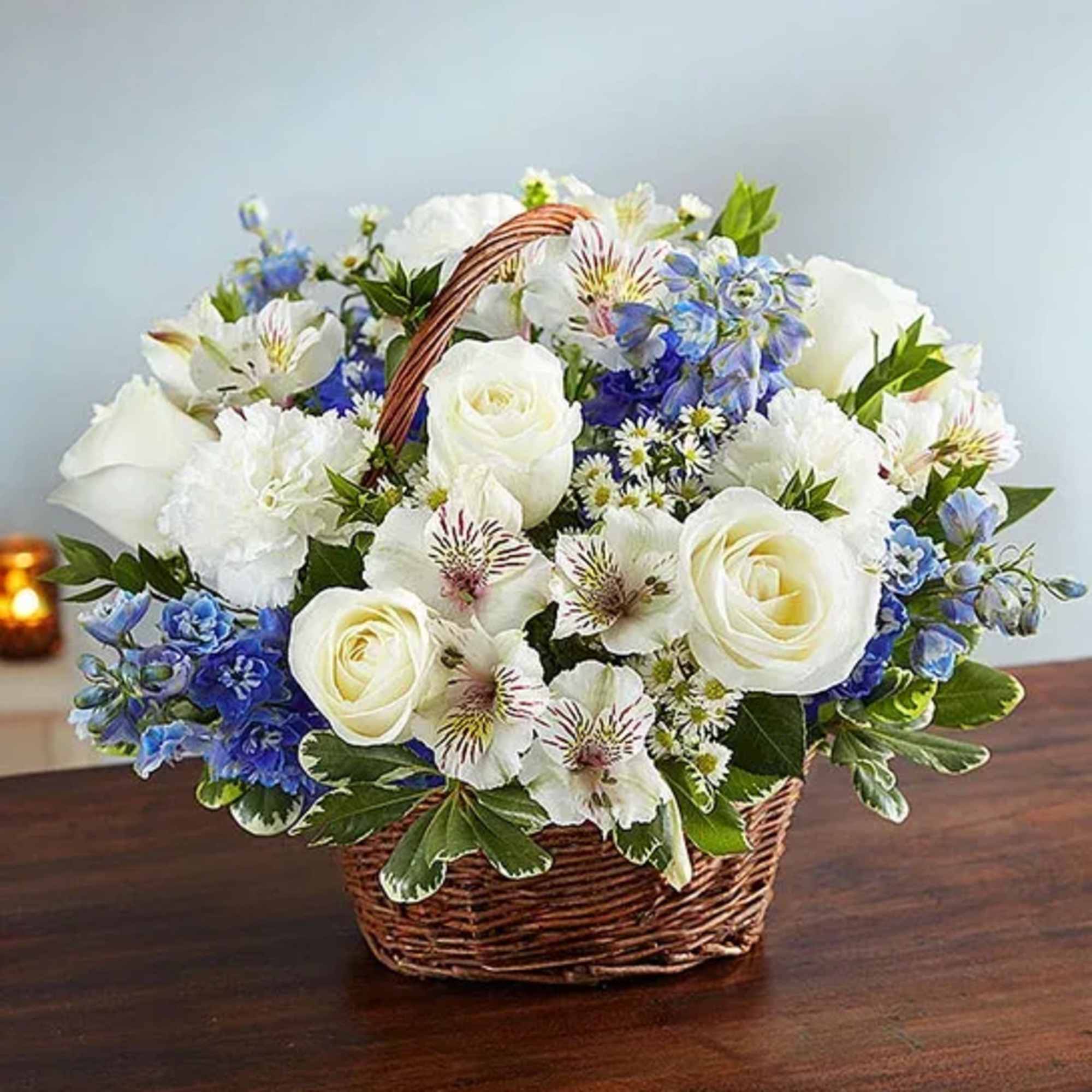 Basket of white roses and blue flowers on a table