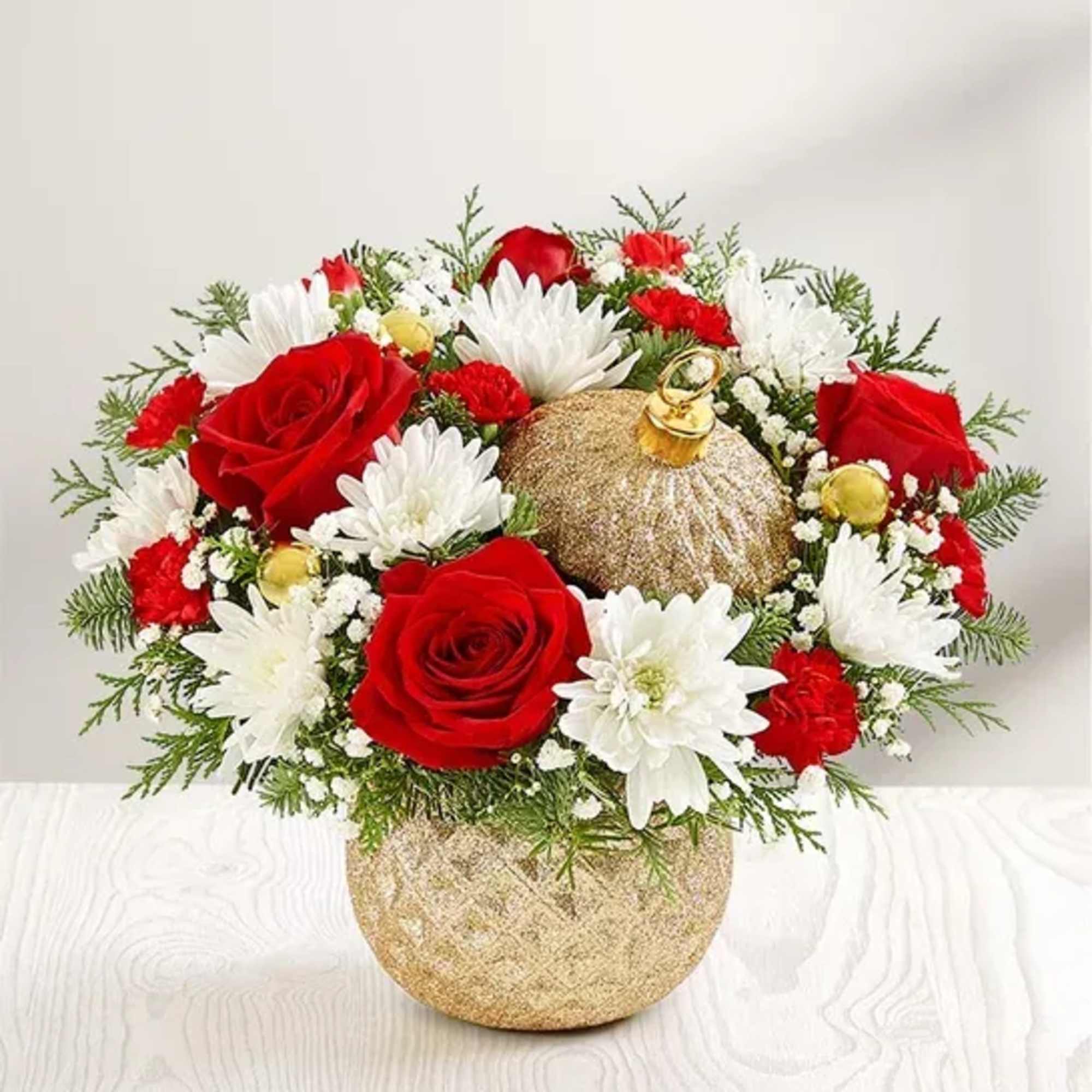 Red roses and white daisies in a gold vase with a glittery ornament